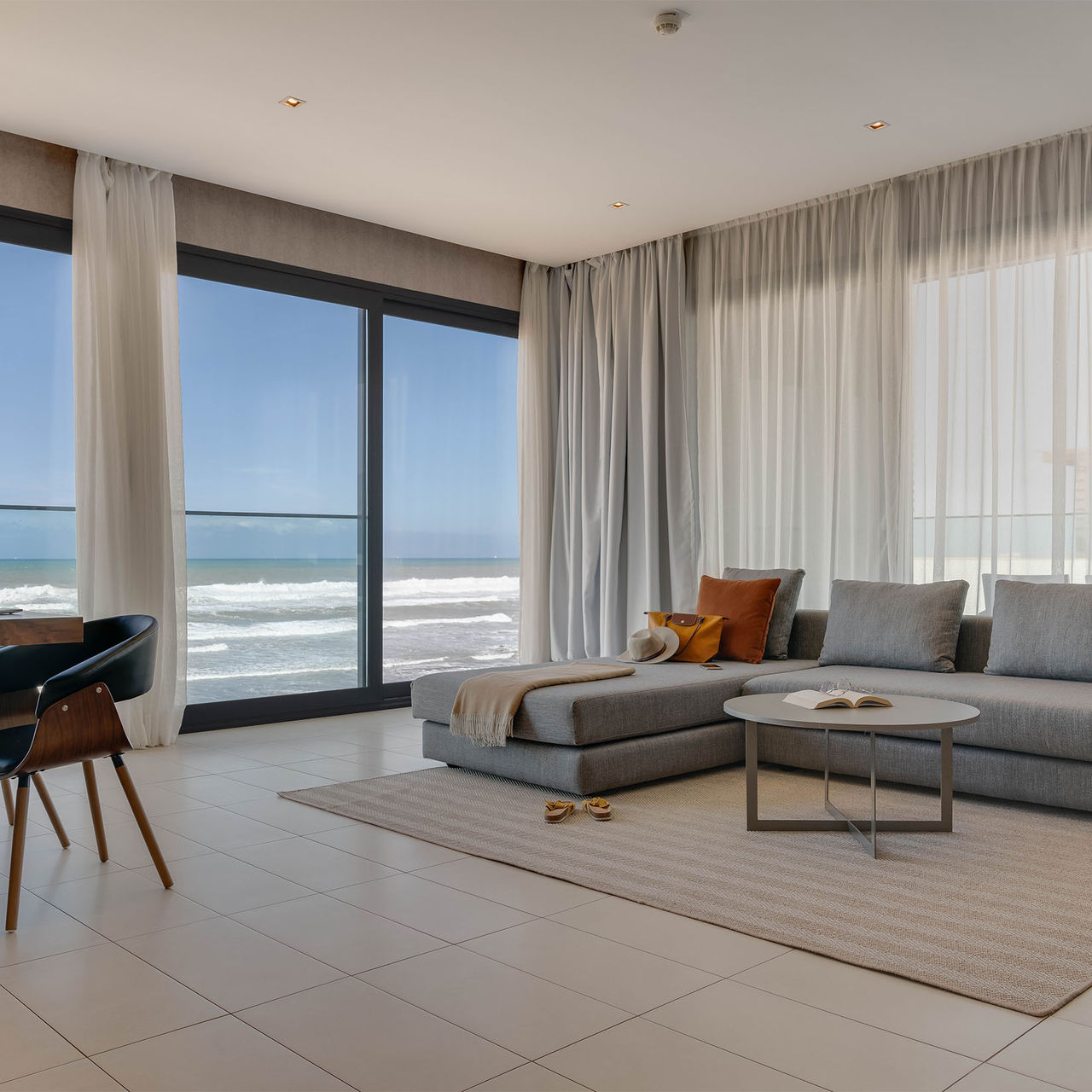Sala con vista al mar, un sofá cómodo y acogedor con chaise lounge y una mesa con sillas de diseño moderno
