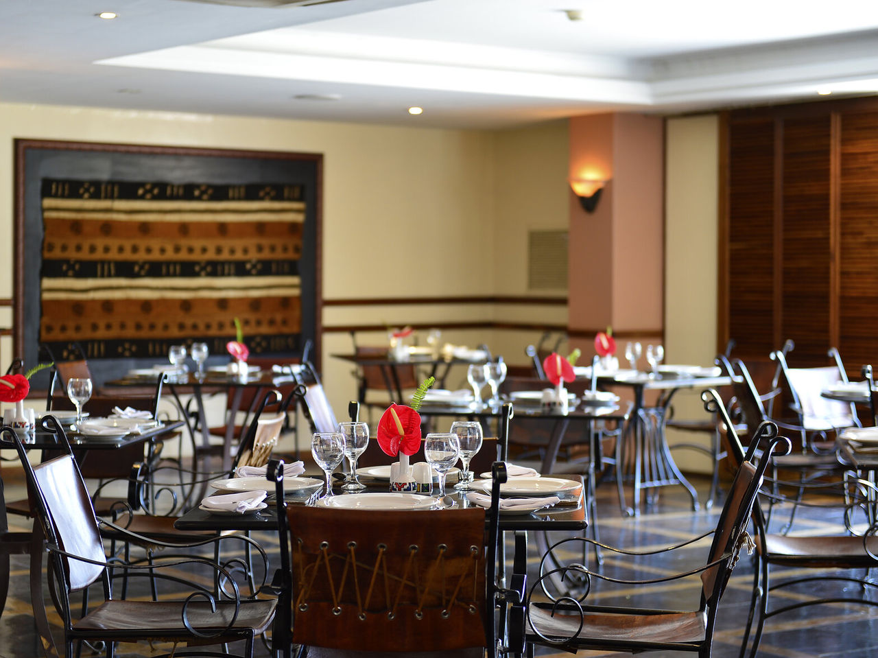 El restaurante Piazza del Campo, del Hotel 4 Estrellas en Maputo, tiene varias mesas con una flor roja y sillas