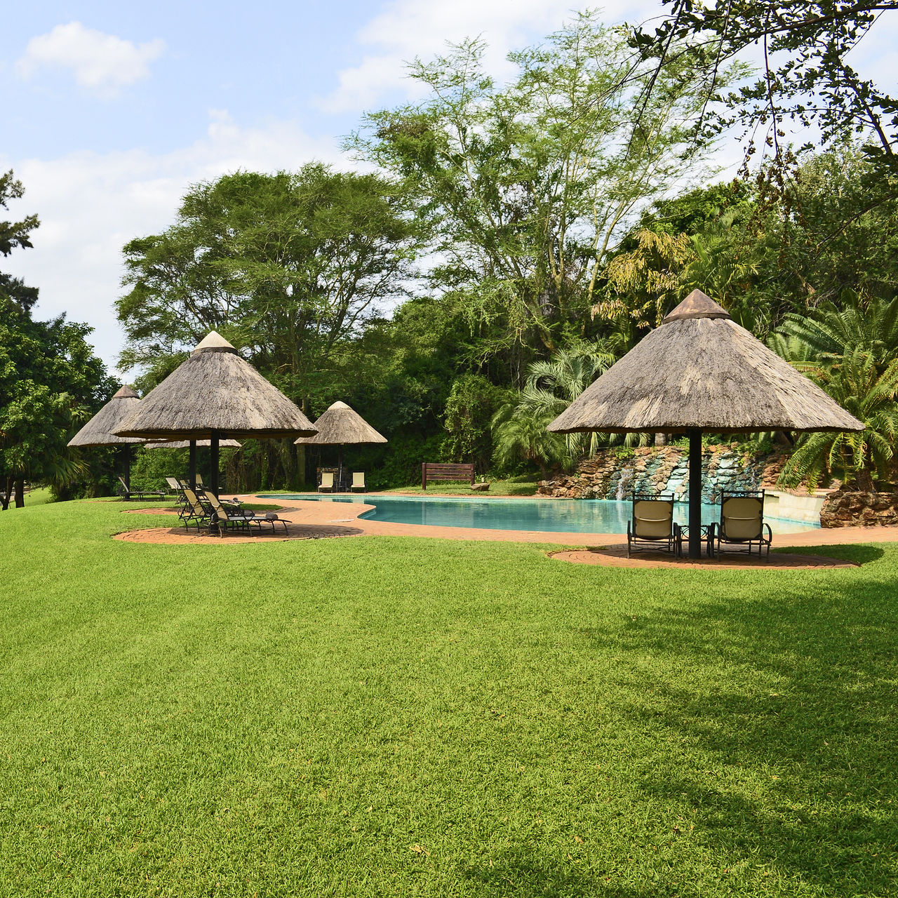 Jardín, piscina exterior y tumbonas del Pestana Kruger Lodge, un hotel de 4 Estrellas en el Parque Kruger