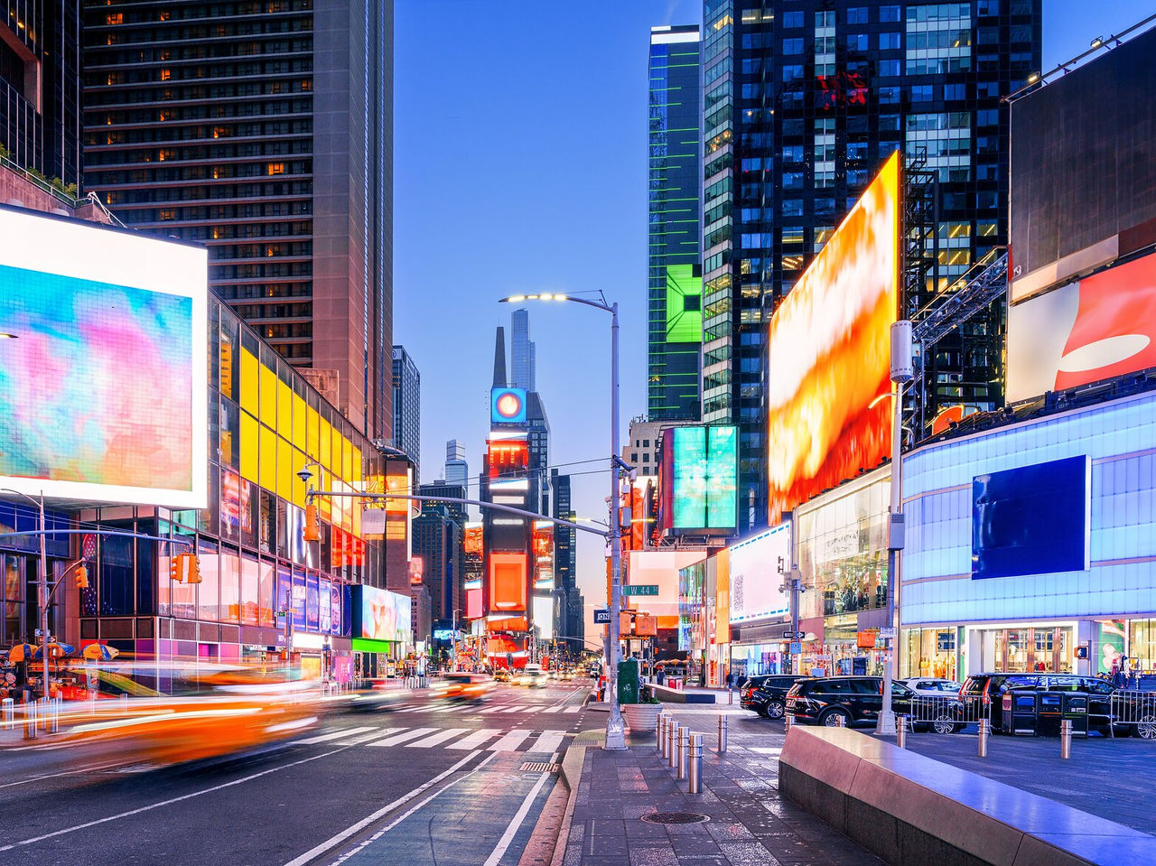 Explora Hoteles en Nueva York con vistas a avenidas iluminadas y pantallas gigantes en Times Square al anochecer