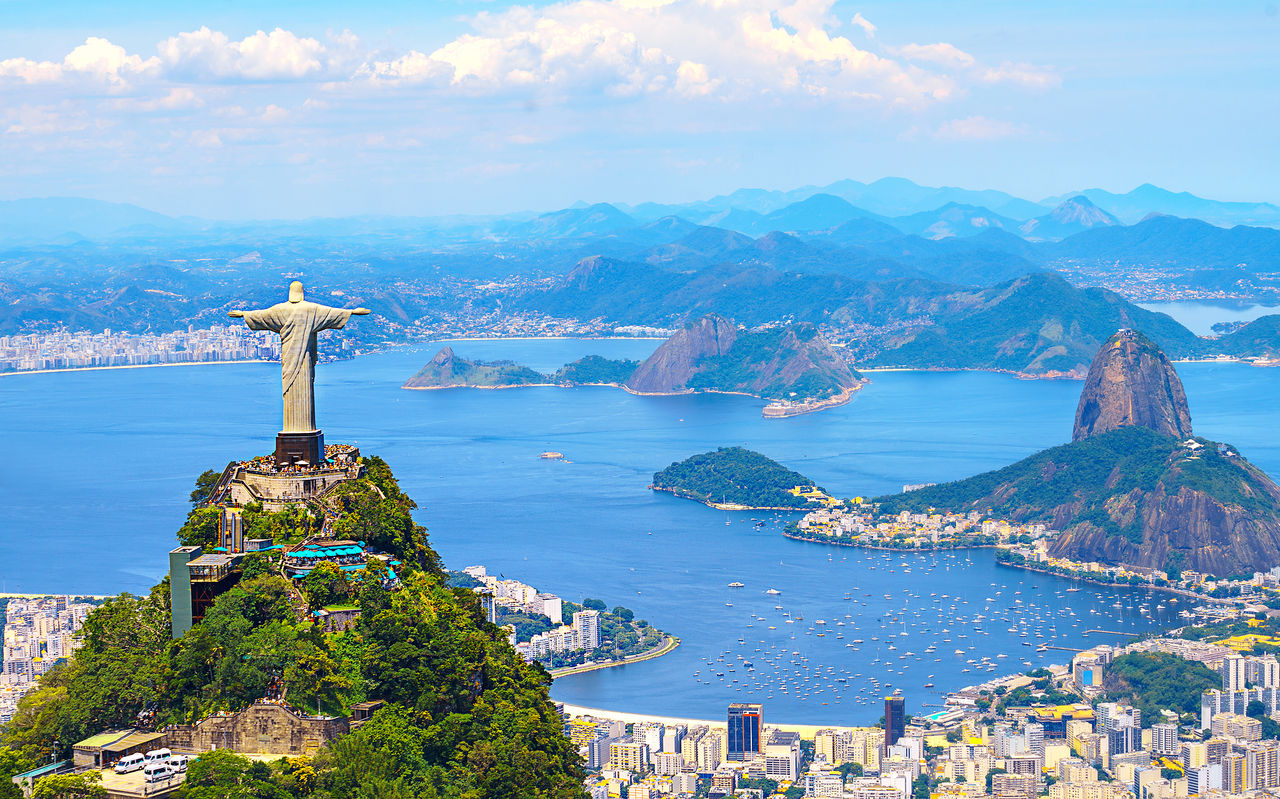 Icónica estatua del Cristo Redentor en Río de Janeiro, con la ciudad, el océano y la playa de fondo.