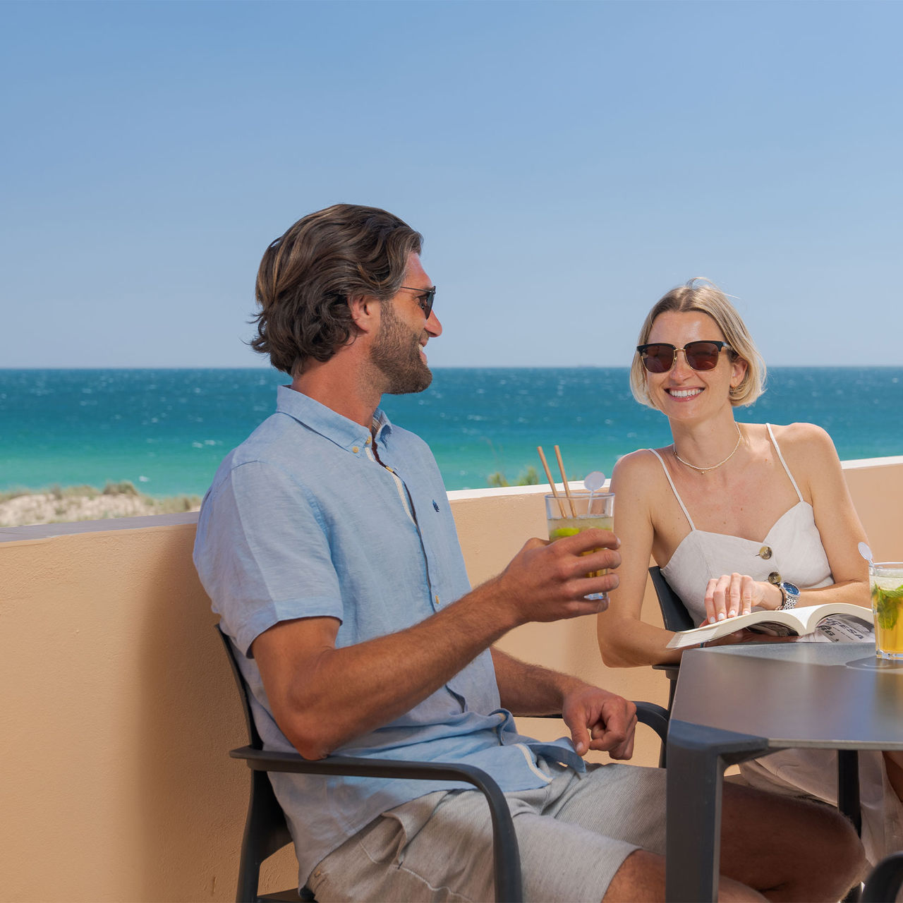 Una pareja bebiendo un zumo en el balcón de una villa privada en las Pestana Alvor Beach Villas, con vista al mar