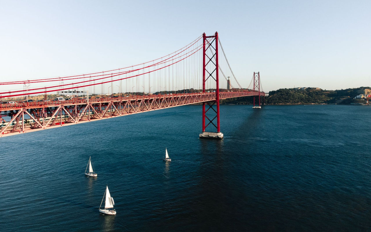 Vista panorámica de la ciudad de Lisboa, con el río Tejo y varios barcos, y el puente 25 de Abril
