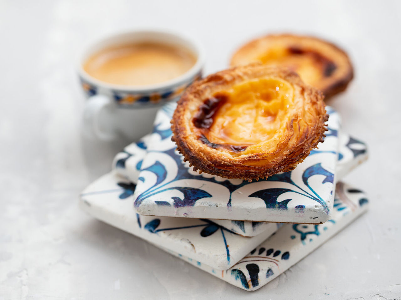 Explora Hoteles en Lisboa con café y pasteles de nata dorados sobre azulejos portugueses estampados