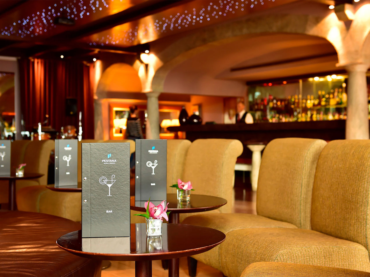 El bar Taverna, del Hotel 5 Estrellas en Madeira, tiene bancos con mesas y un jarrón de flores