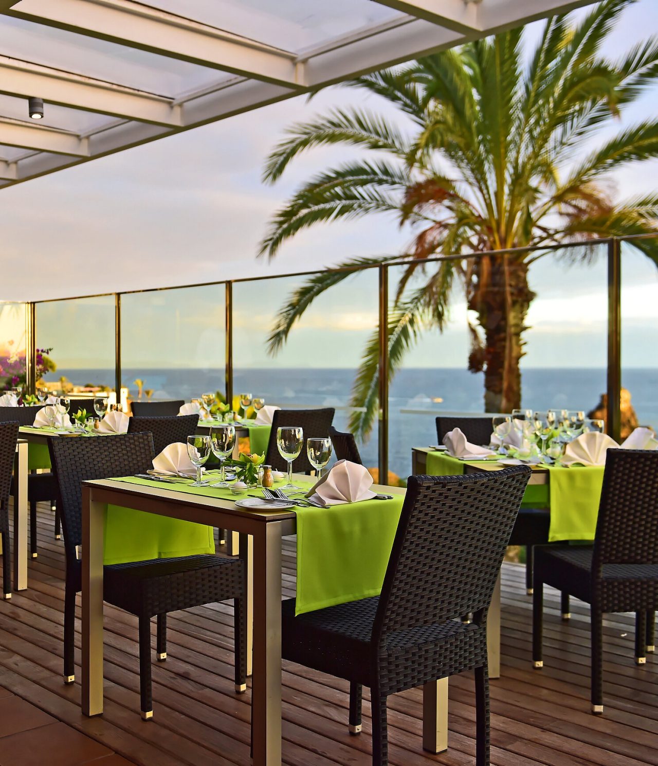 El restaurante The Deck, del Hotel 4 Estrellas junto al mar en Funchal, tiene mesas con mantel verde y vista al mar