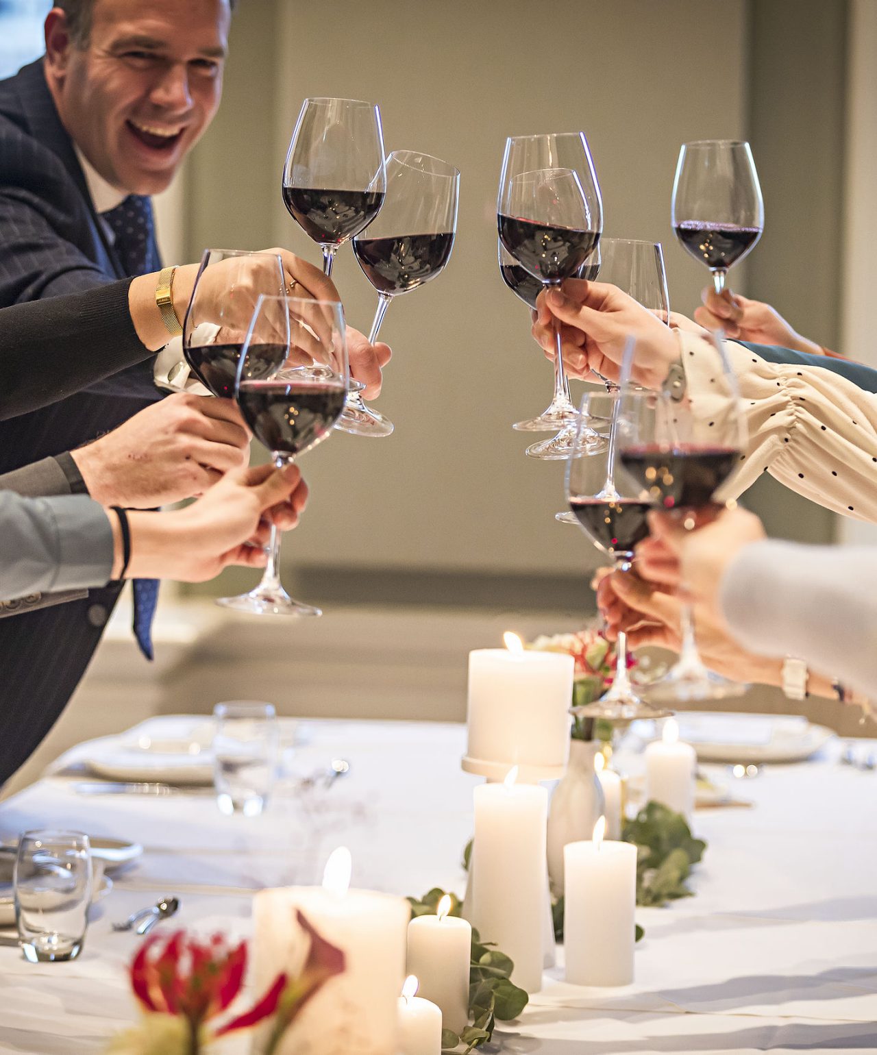Los invitados brindan con copas de vino tinto en una boda con decoración elegante en el Pestana Hotel Group
