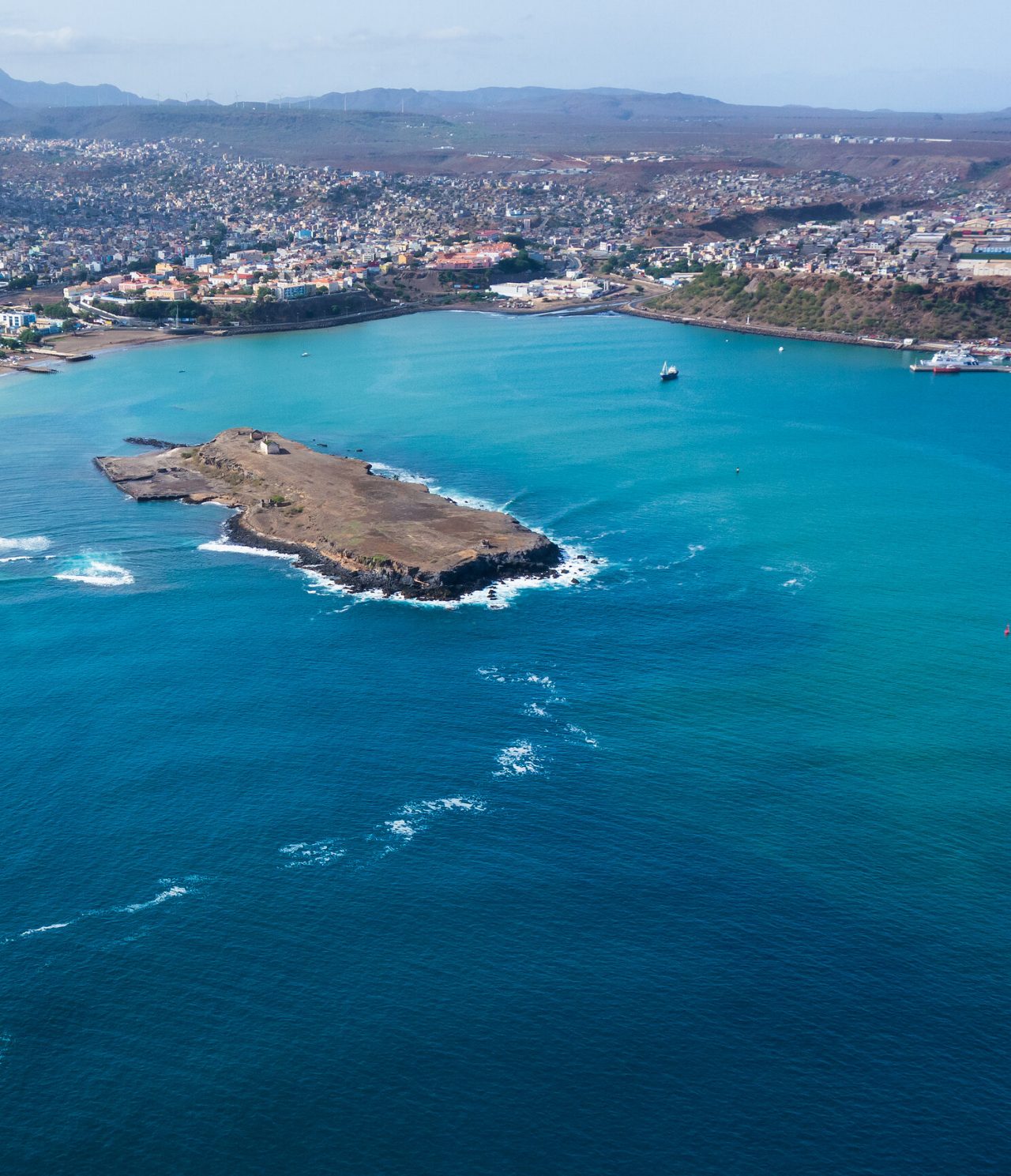 Vista aérea da Cidade da Praia onde contrasta o azul do oceano e a paisagem urbana e colorida