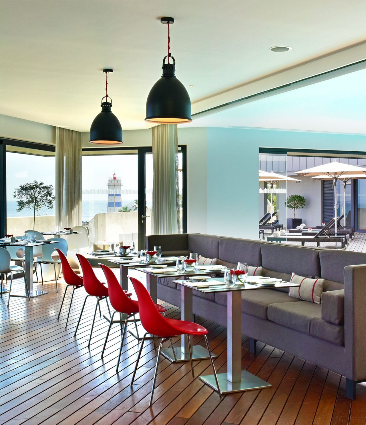 O restaurante Maris Stella, do Hotel 5 Estrelas em Cascais, tem um sofá cinzento com mesas e cadeiras vermelhas