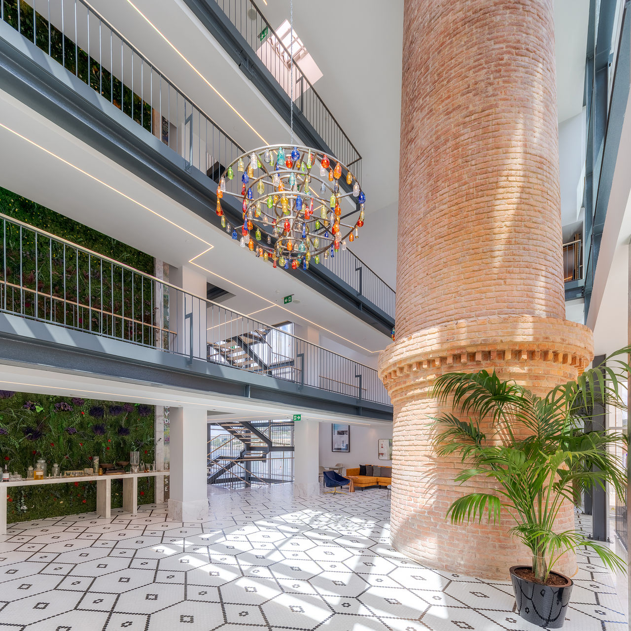 Hall de entrada do Pestana Douro Riverside, com uma chaminé de tijolo e um lustre de vidro colorido