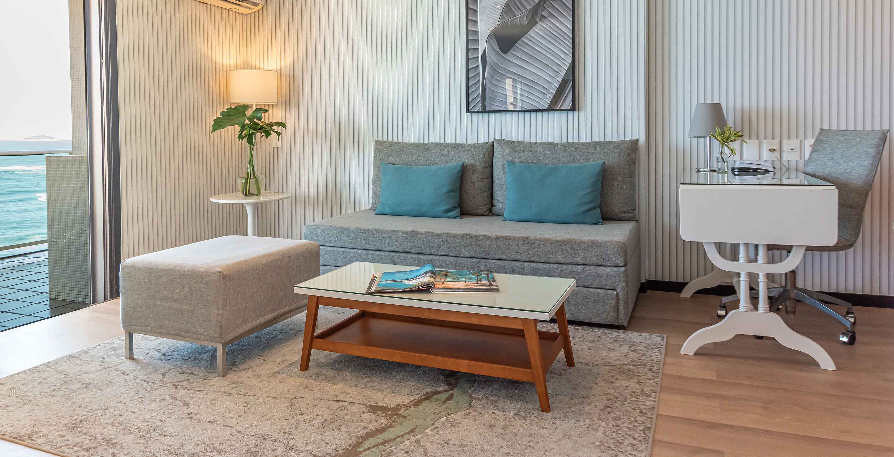 Die Ozeanische Suite im Pestana Rio Atlântica hat modernes Wohnzimmer mit Sofa, Schreibtisch und Meerblick.