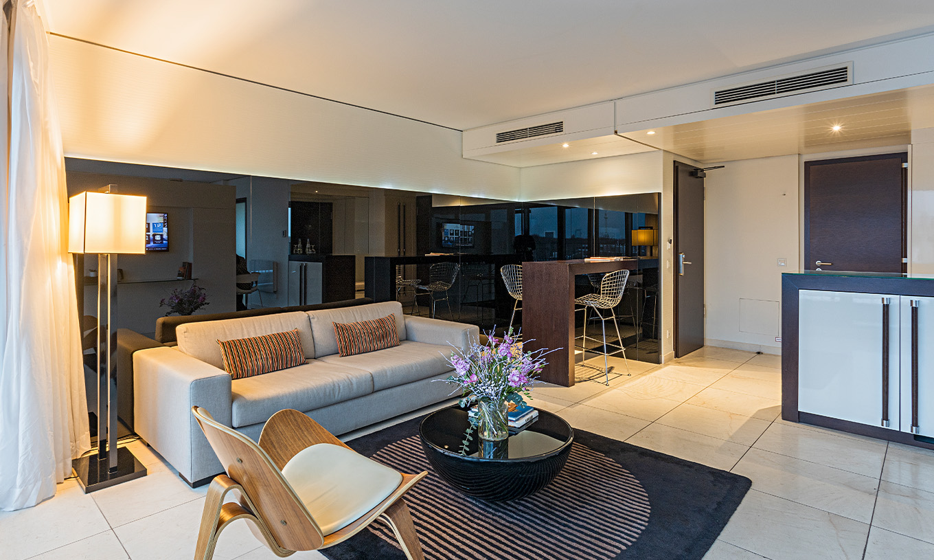 Die Panoramasuite im Pestana Berlin Tiergarten hat ein Sofa mit Lampe, Couchtisch und eine Bar mit Stühlen