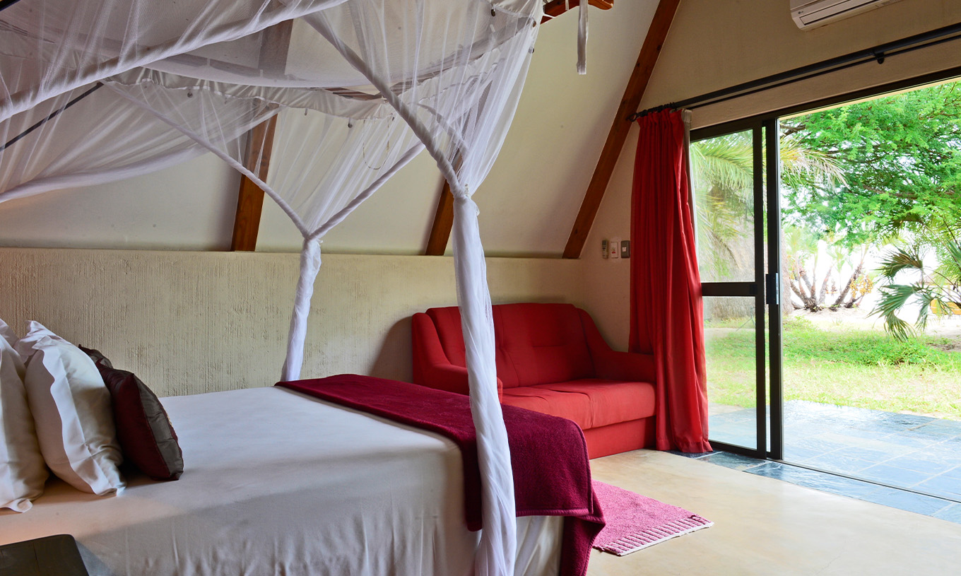 Die Bungalow Suite T2 im Pestana Bazaruto Lodge hat ein Bett mit Baldachin und Gartenblick und ein Doppelsofa