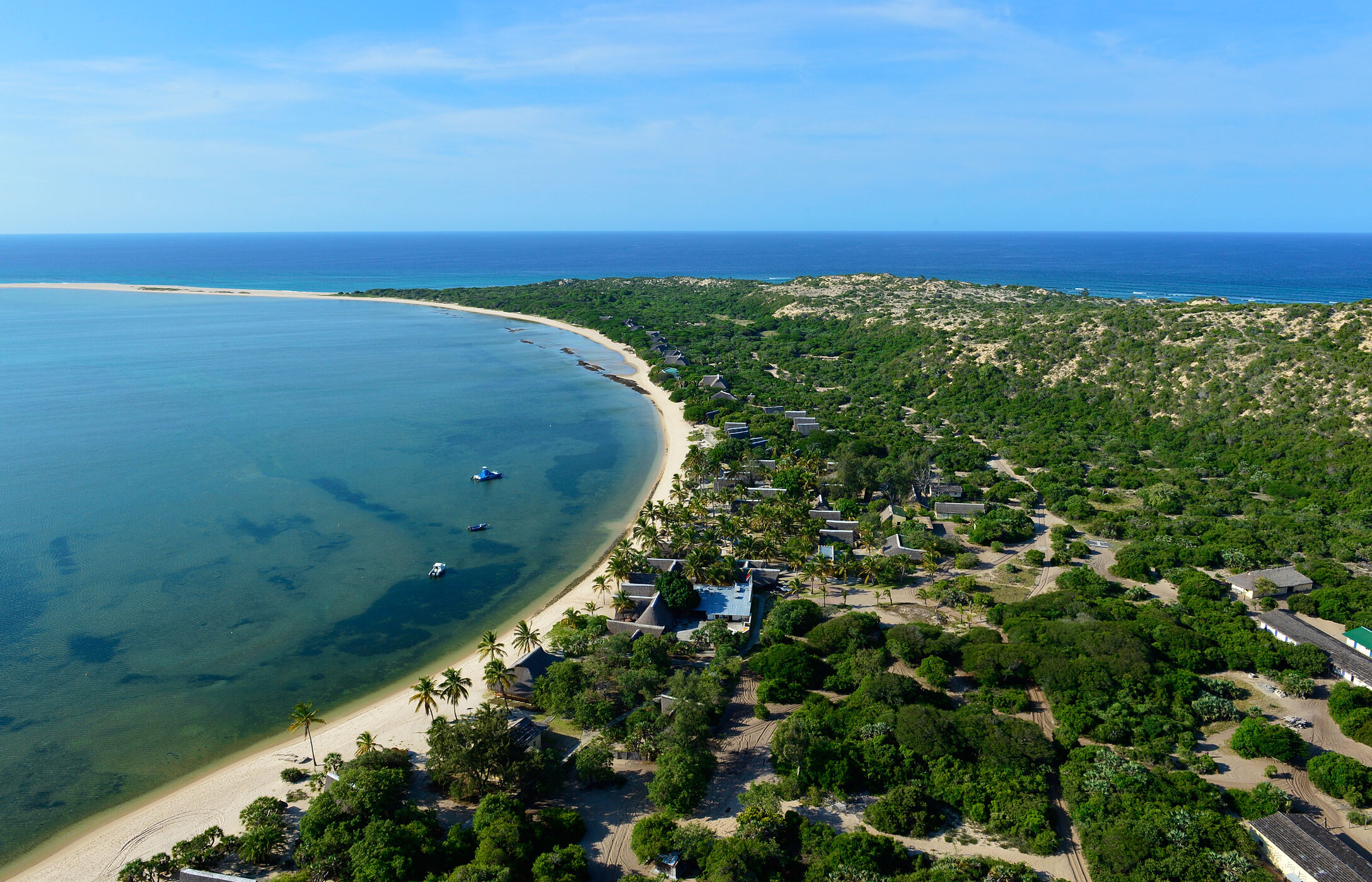 Luftaufnahme der Insel Bazaruto in Mosambik, mit einem weißen Sandstrand, umgeben von Vegetation und einigen Gebäuden.