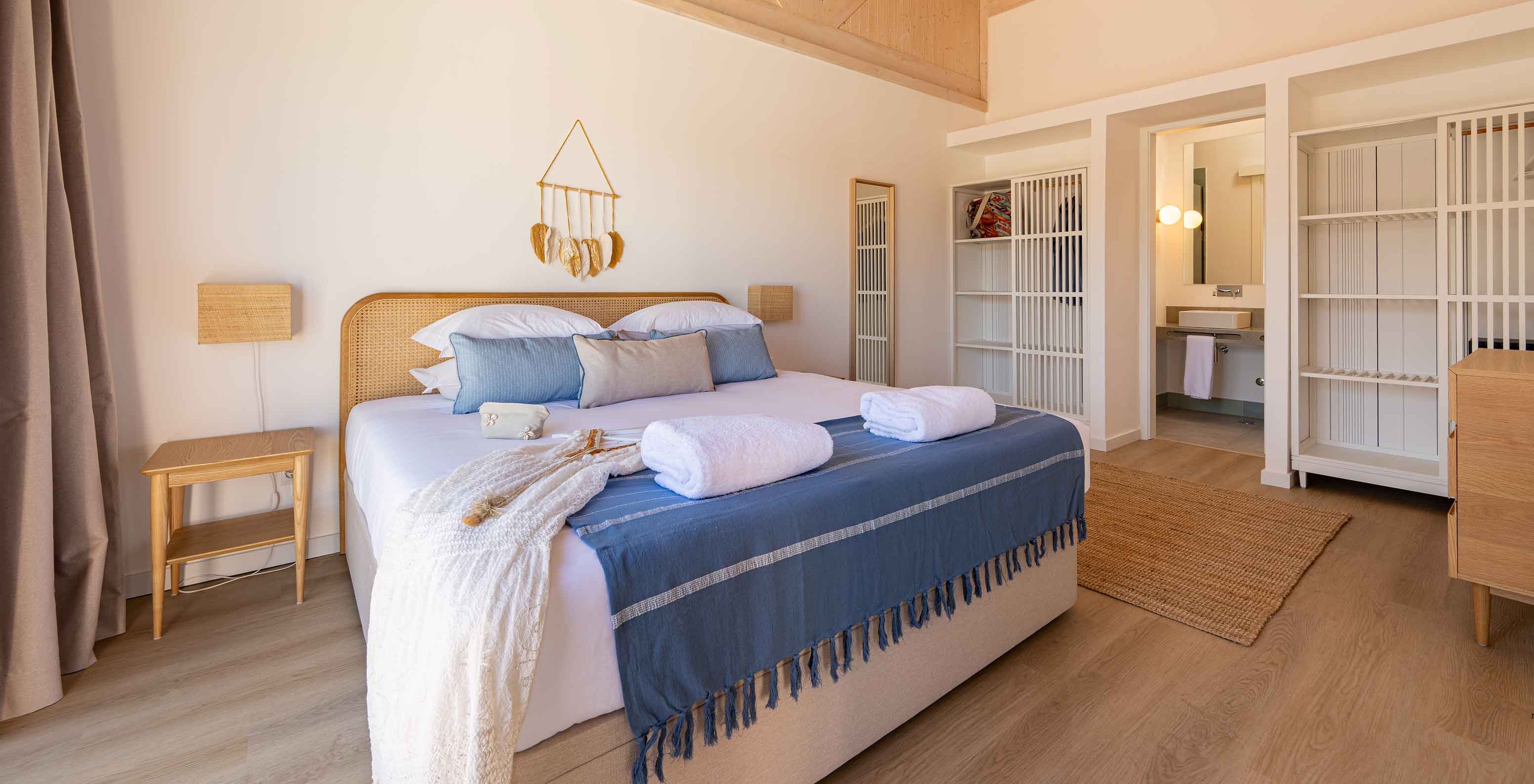 Die Premium Green Villa im Pestana Comporta Village Residences hat ein Schlafzimmer mit Doppelbett und mehreren blauen Kissen