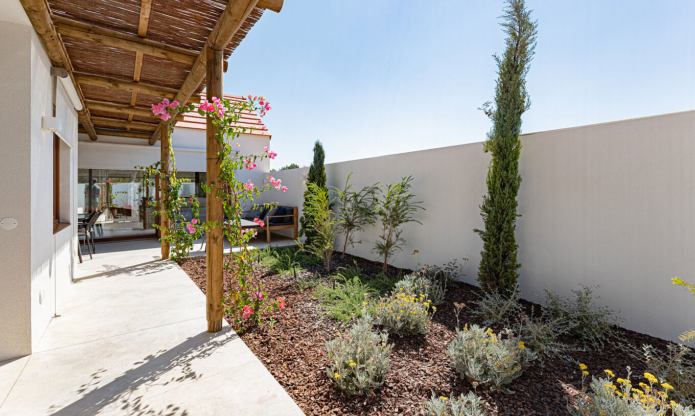 Die Standard Villa T2 im Pestana Comporta Village Residences verfügt über einen Garten mit Pflanzen und einer Holzpergola.