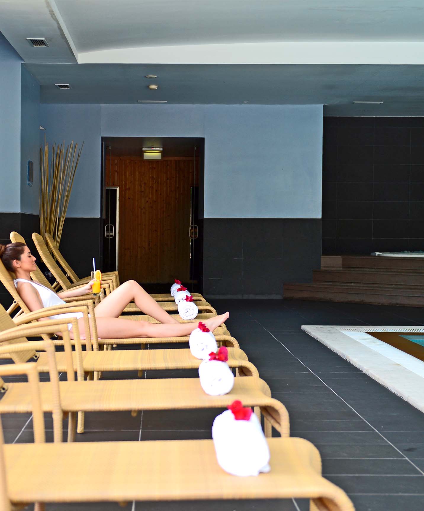 Innenpool mit Metallleitern und Jacuzzi, mit Liegen und Handtüchern und einer liegenden Frau