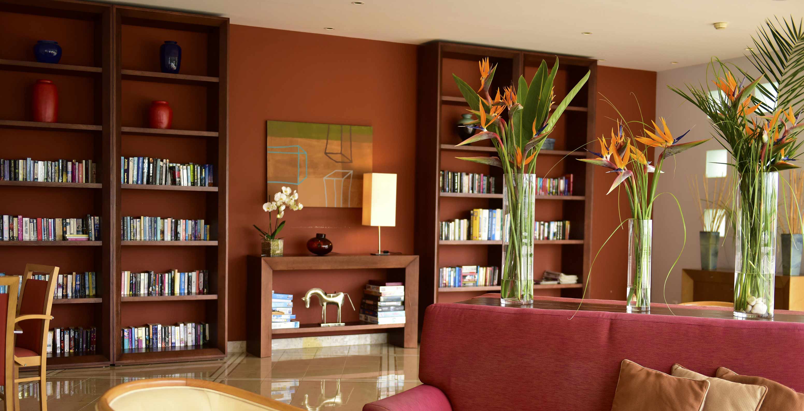 Bibliothek mit Bücherregalen, Blumenvasen und einem Sofa im Pestana Alvor Park, einem 4-Sterne-Aparthotel in Alvor mit Pool