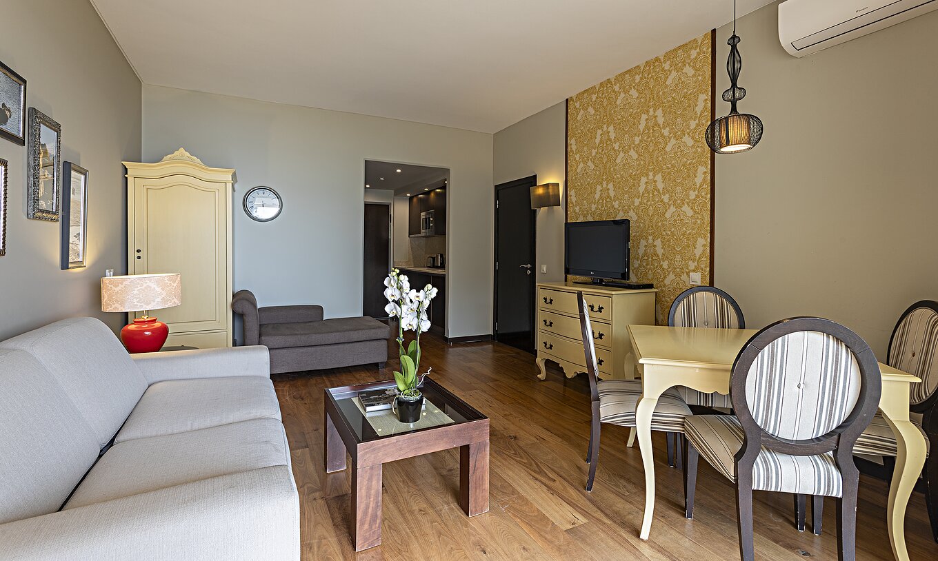 Die Cliff Suite T1 im Pestana Alvor Praia verfügt über ein Wohnzimmer mit einem Sofa, Tapeten, Fernseher und einem Esstisch