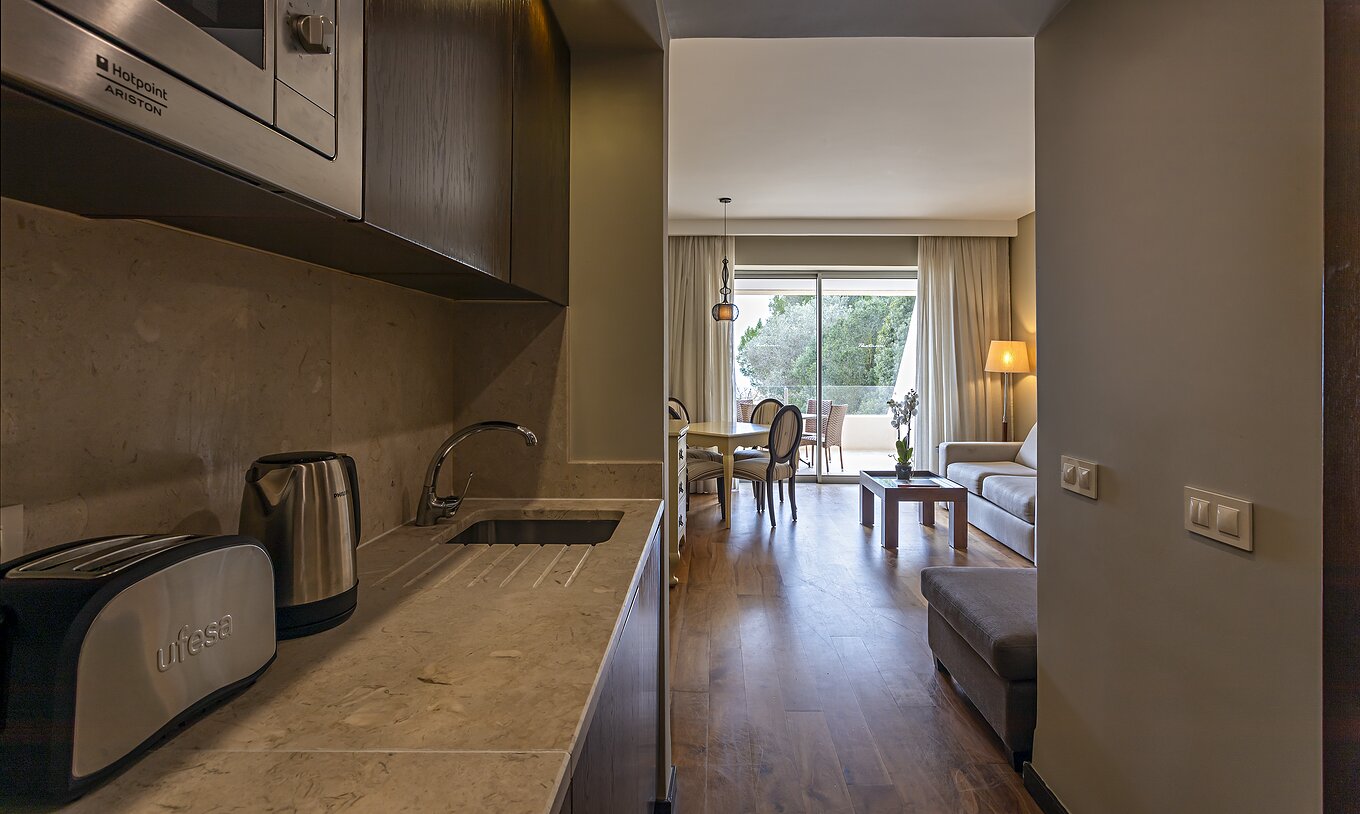 Die Cliff Suite T1 im Pestana Alvor Praia hat eine Küche mit Zugang zum Wohnzimmer sowie Wasserkocher, Toaster und Mikrowelle