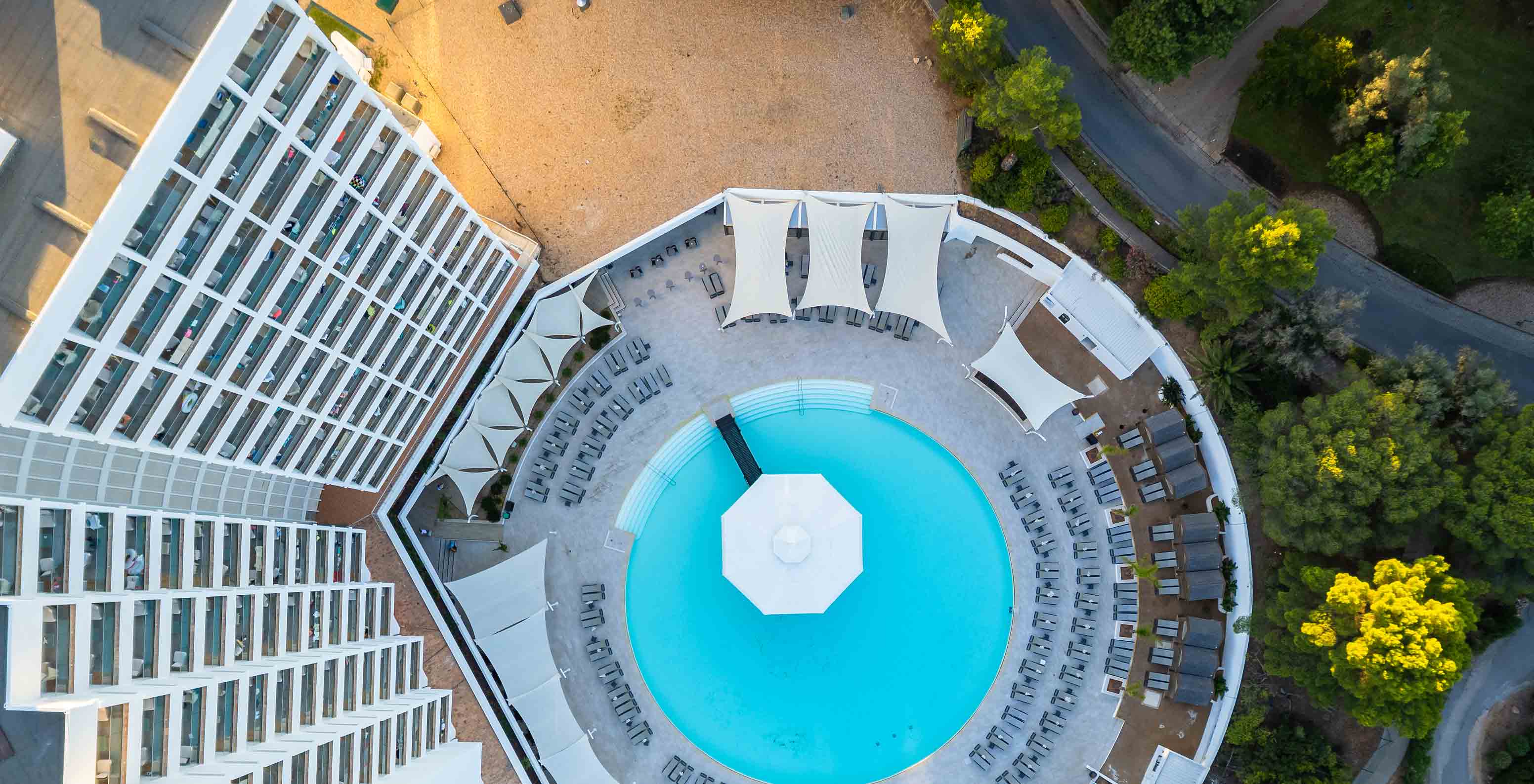 Luftaufnahme des Pools im Pestana Blue Alvor Beach, umgeben von Sonnenliegen mit Sonnenschirmen
