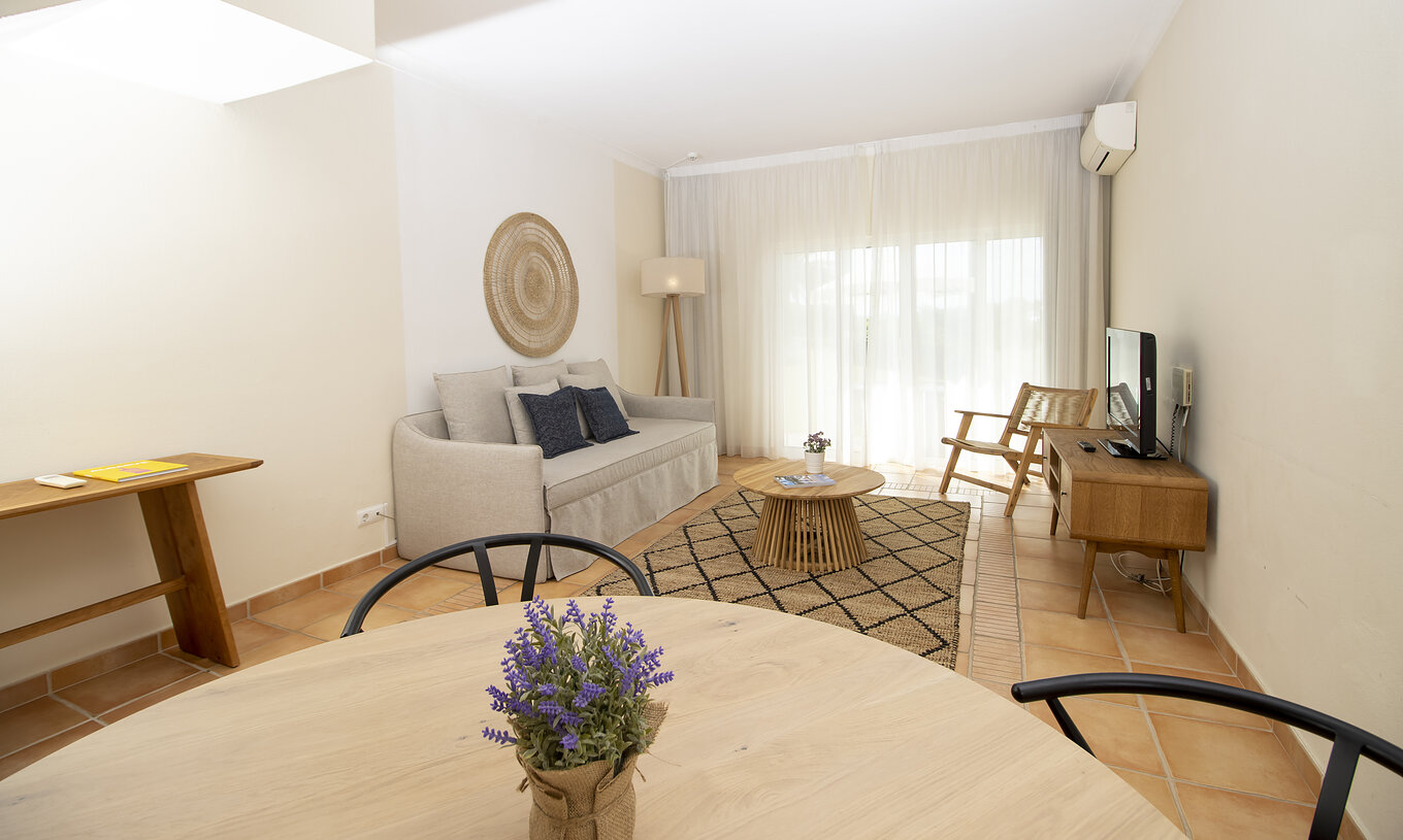 Das T2 Superior Appartement im Pestana Palm Gardens hat ein Zimmer mit rundem Tisch, Sofa, Fernseher und Fenster