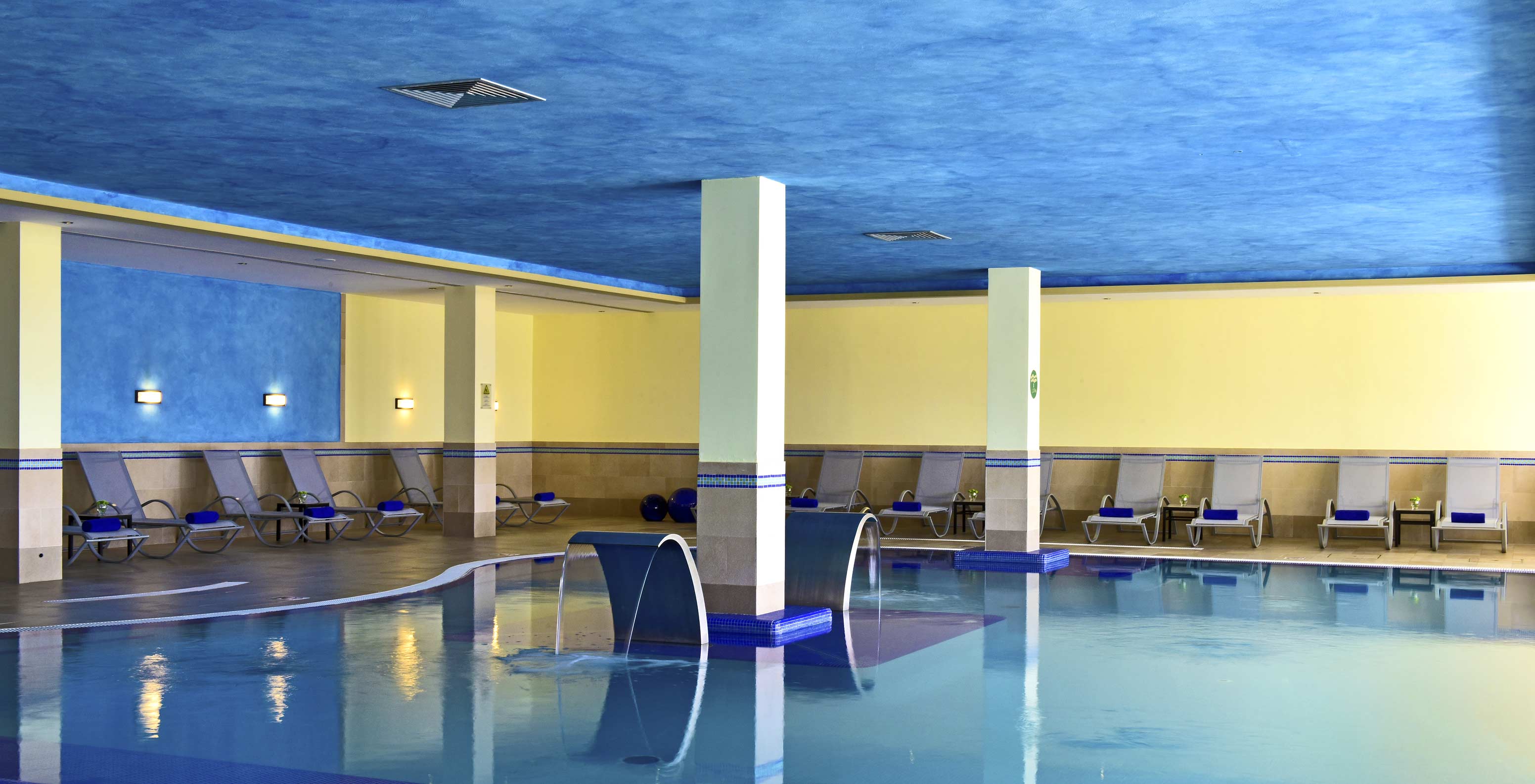 Innenpool des Pestana Viking, blaue und gelbe Wände, ruhige Atmosphäre, mit mehreren Liegestühlen