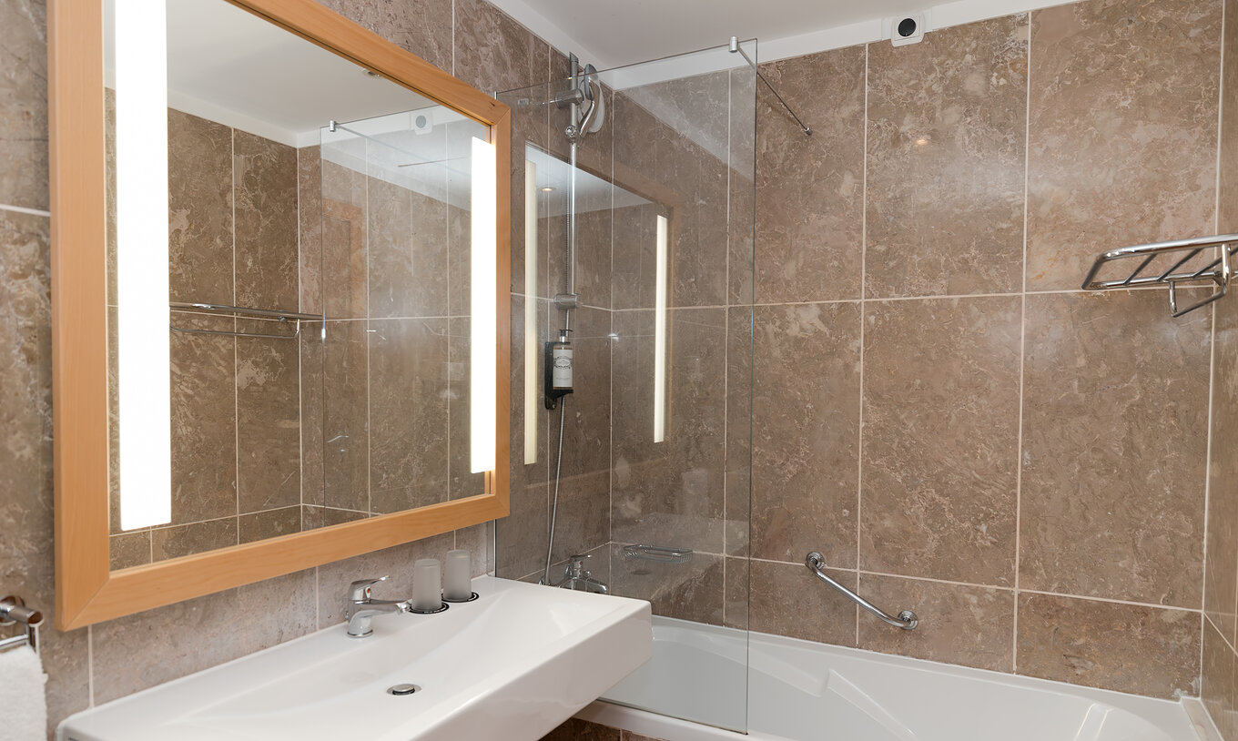 Das Deluxe Meerblick im Pestana Viking hat ein Bad mit Waschbecken, großem Spiegel und Badewanne mit Dusche