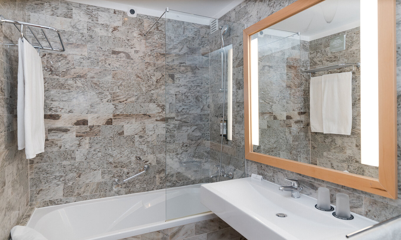 Die Superior Suite Meerblick im Pestana Viking hat ein Bad mit Waschbecken, großem Spiegel und Badewanne mit Dusche