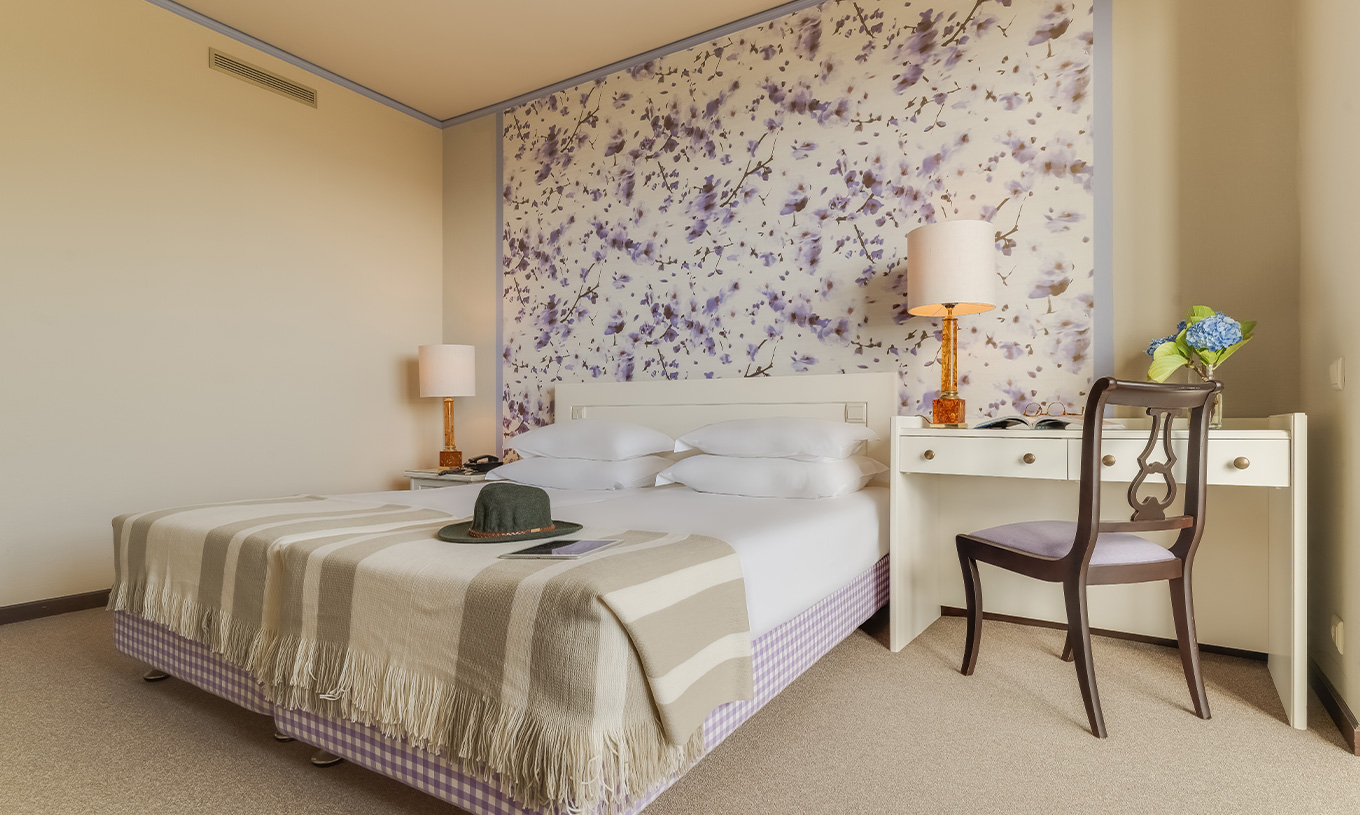 Das Standard Gartenblick Zimmer im Pestana Bahia Praia hat ein Bett mit vier Kissen und einen Schreibtisch mit Stuhl