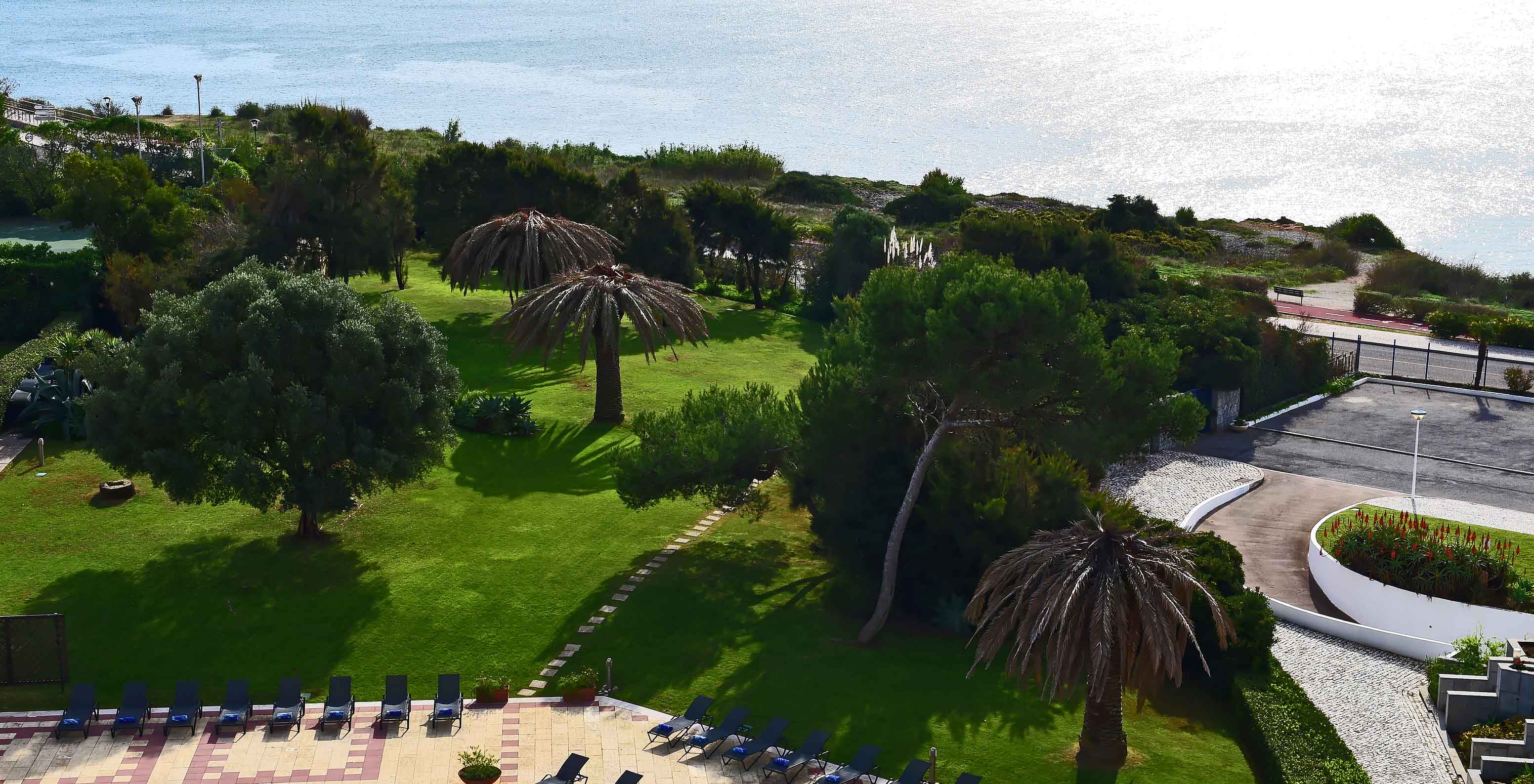 Blick aus dem Hotelzimmer des Pestana Cascais, wo man das Meer und den Garten des Hotels mit einigen Sonnenliegen sehen kann.