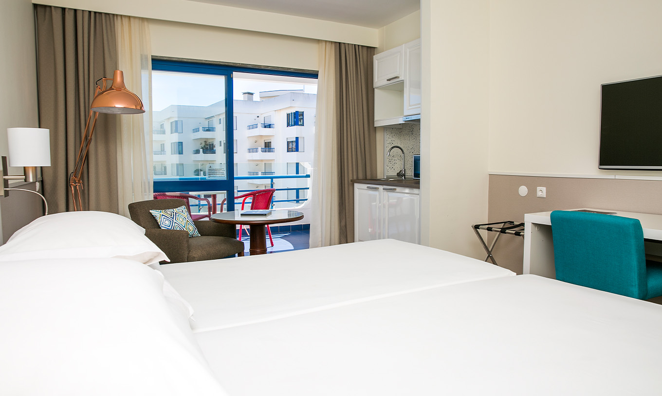 Das Deluxe Superior-Zimmer im Pestana Cascais hat zwei Einzelbetten, TV und einen Balkon mit Stühlen und Tischen