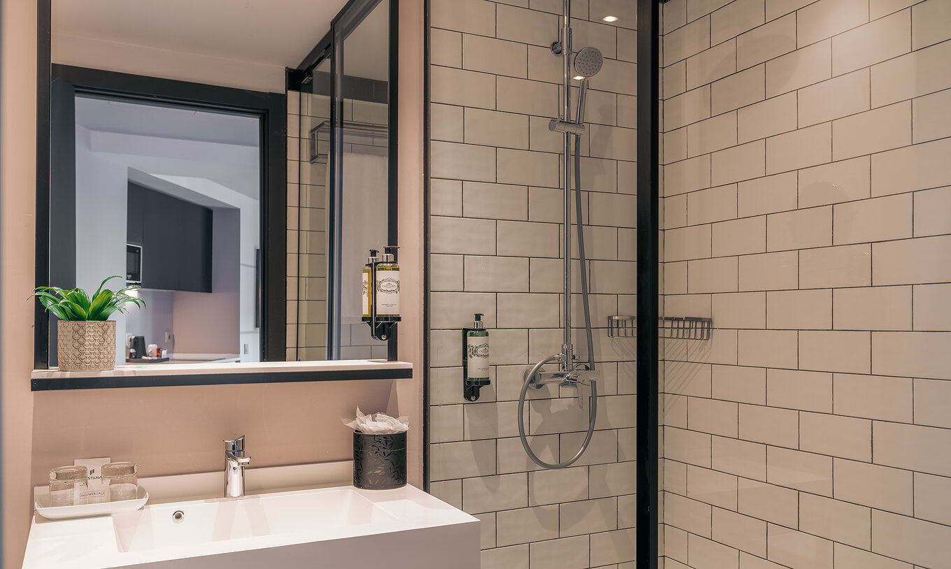 Das Double Deluxe Studio im Pestana Lisboa Vintage hat Dusche mit Glastüren, schwarzen Akzenten und Waschbecken