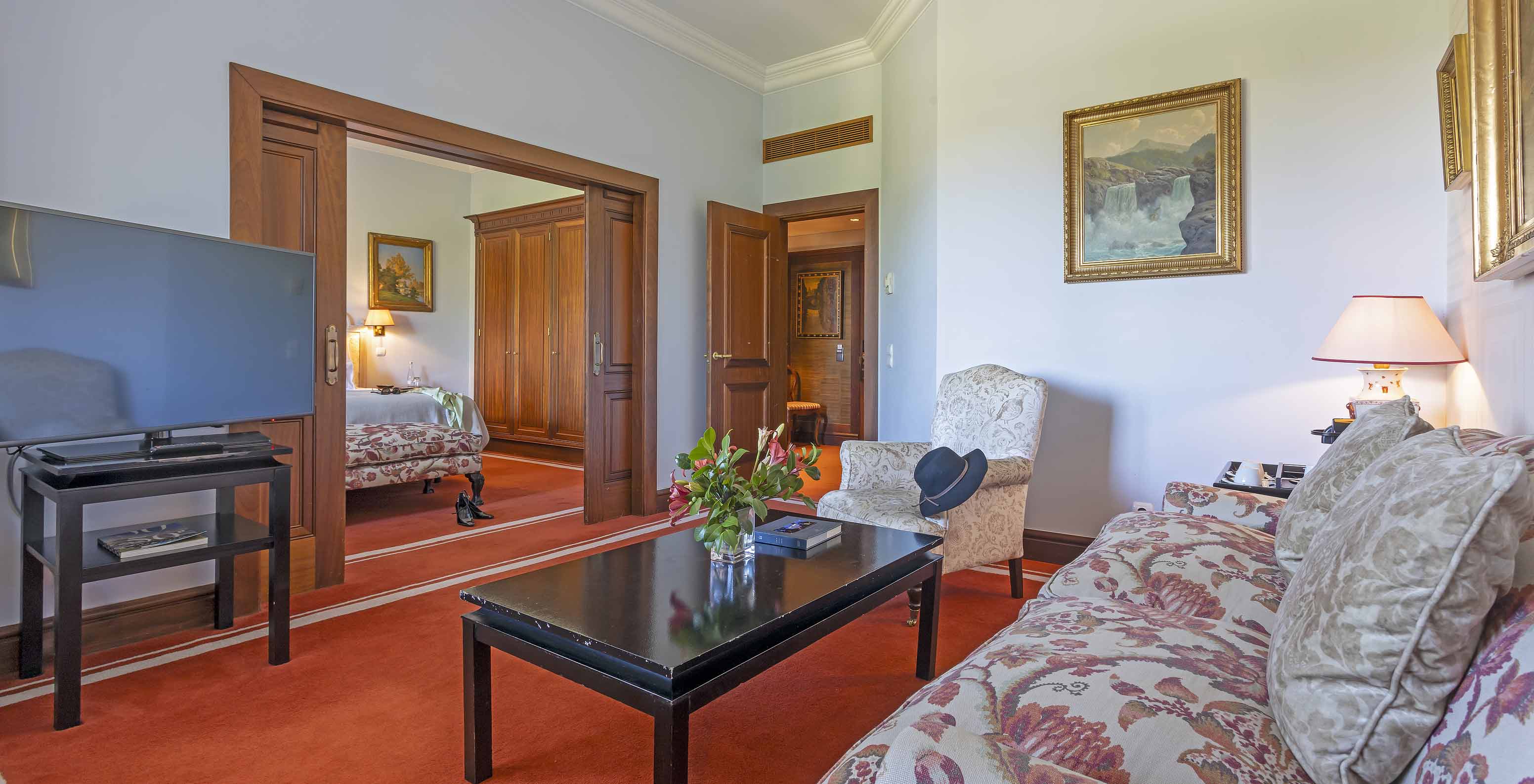 Die Suite im Pestana Palace Lisboa hat ein Wohnzimmer mit Sofa, Sessel, Couchtisch und Fernseher