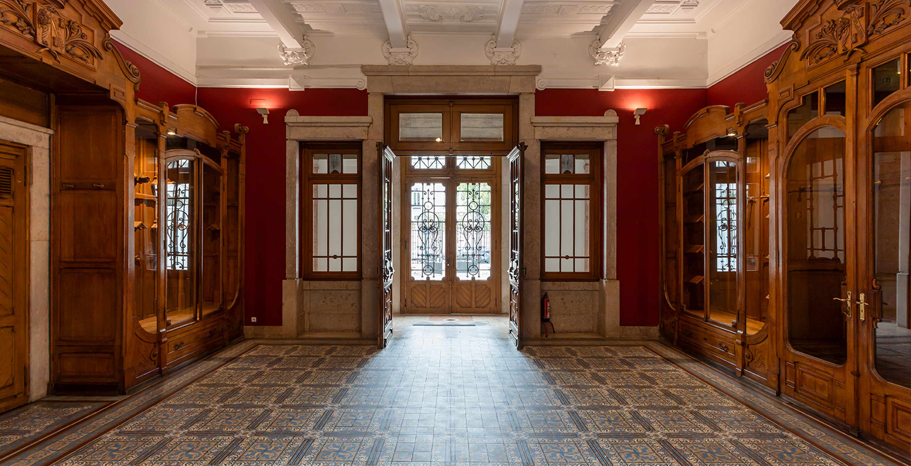 Das Pestana Palace Lisboa hat einen Veranstaltungsraum mit roten Wänden und antiken Holzmöbeln	