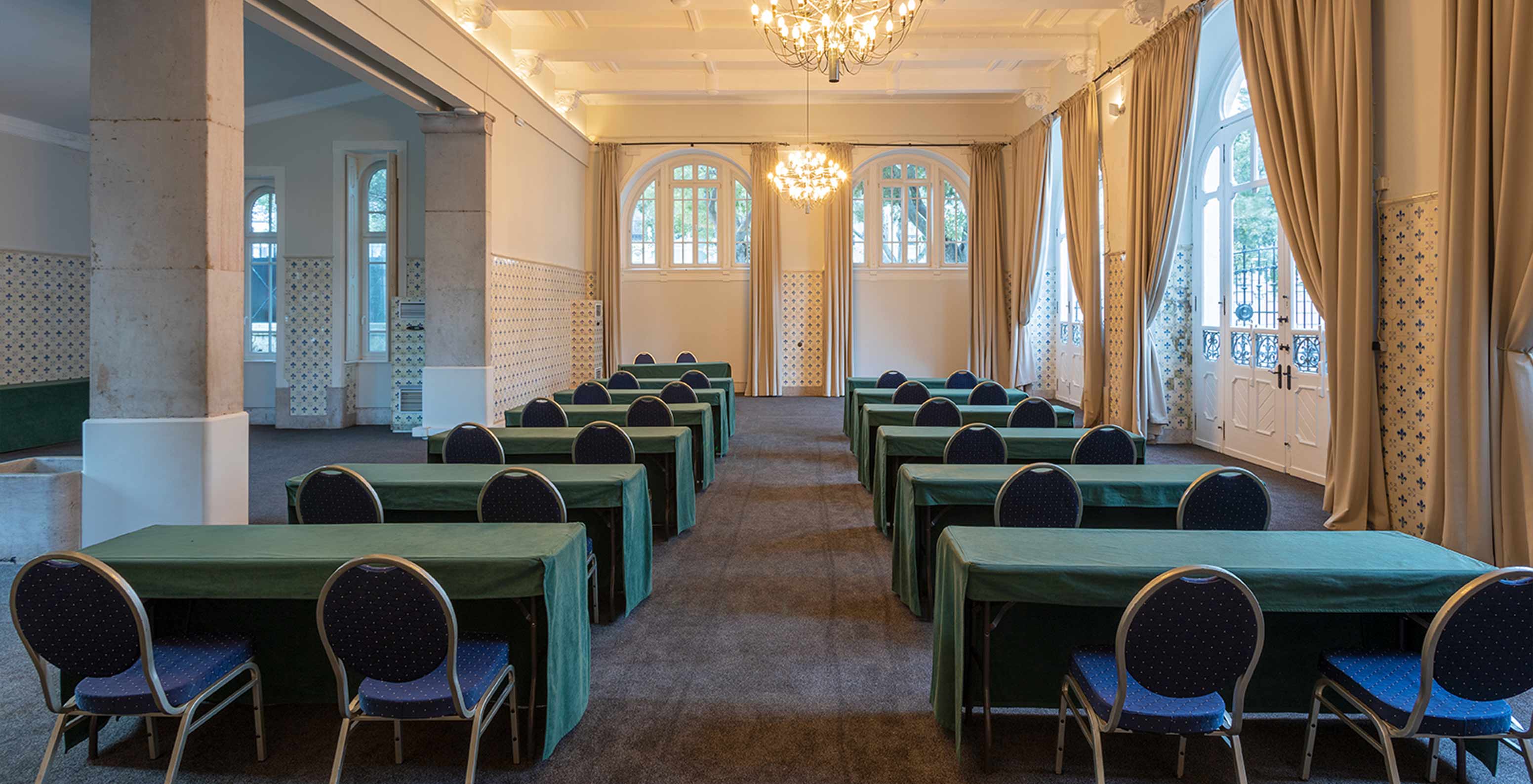 Das Pestana Palace Lisboa hat einen Besprechungsraum mit langen grünen Tischen, blauen Stühlen und mehreren Fenstern