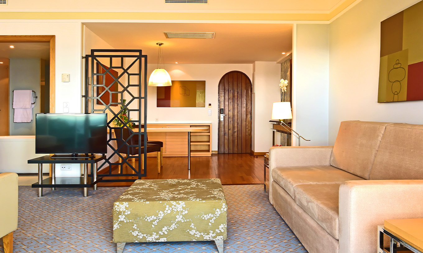 Die Superior Junior Suite im Pestana Carlton Madeira hat ein Wohnzimmer mit Sofa und Fernseher und einen Eingangsbereich