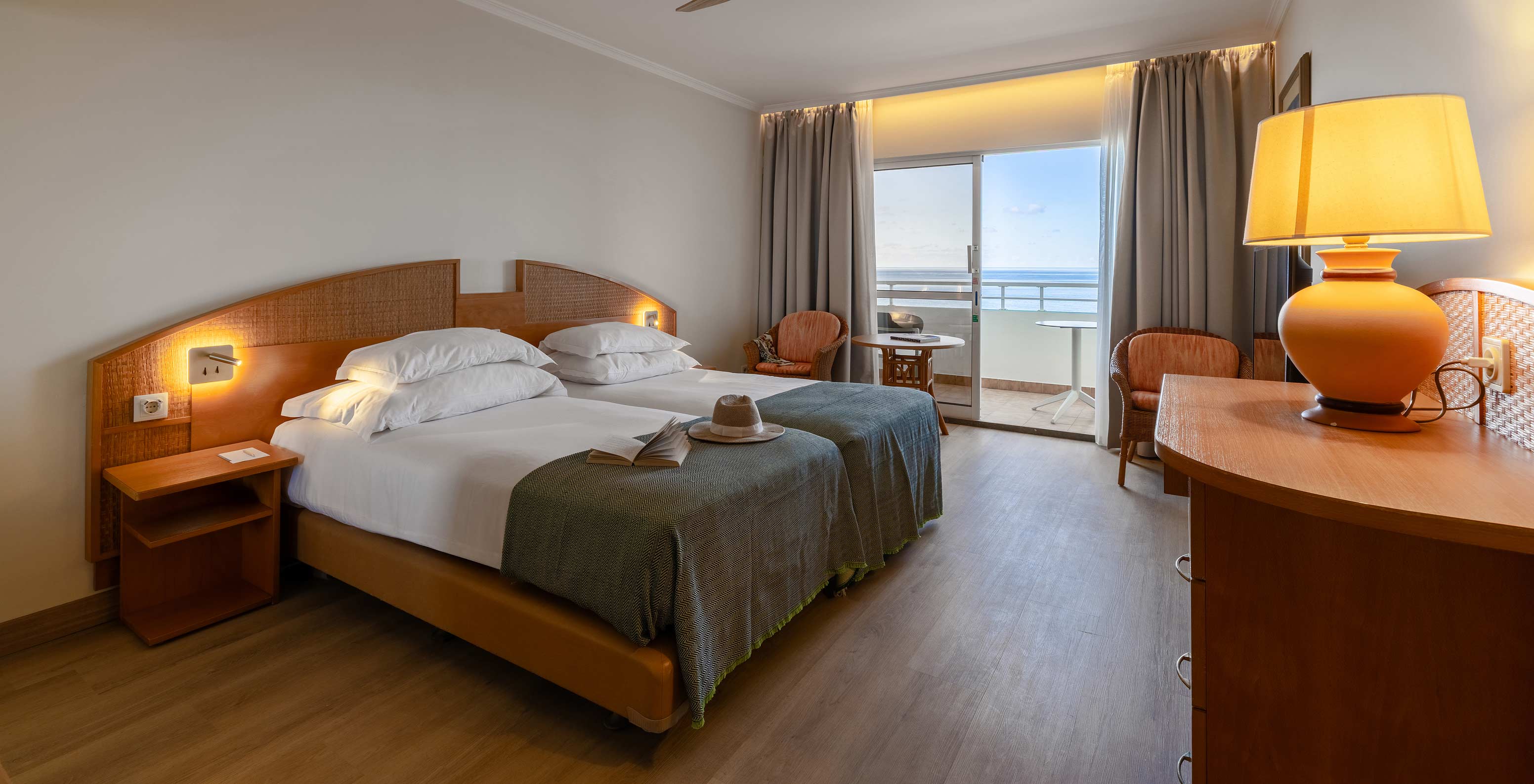 Das Classic Sea View im Pestana Ocean Bay All Inclusive verfügt über ein Doppelbett zwei Stühle und einen Balkon mit Aussicht