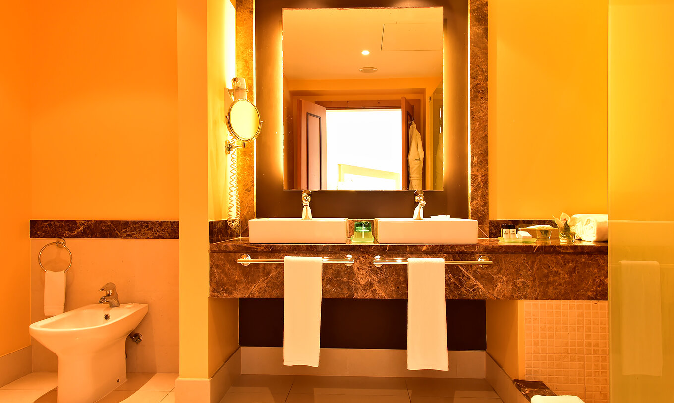 Die Suite hat ein Bad mit braunem Rahmen Spiegel, zwei Waschbecken und Bidet 