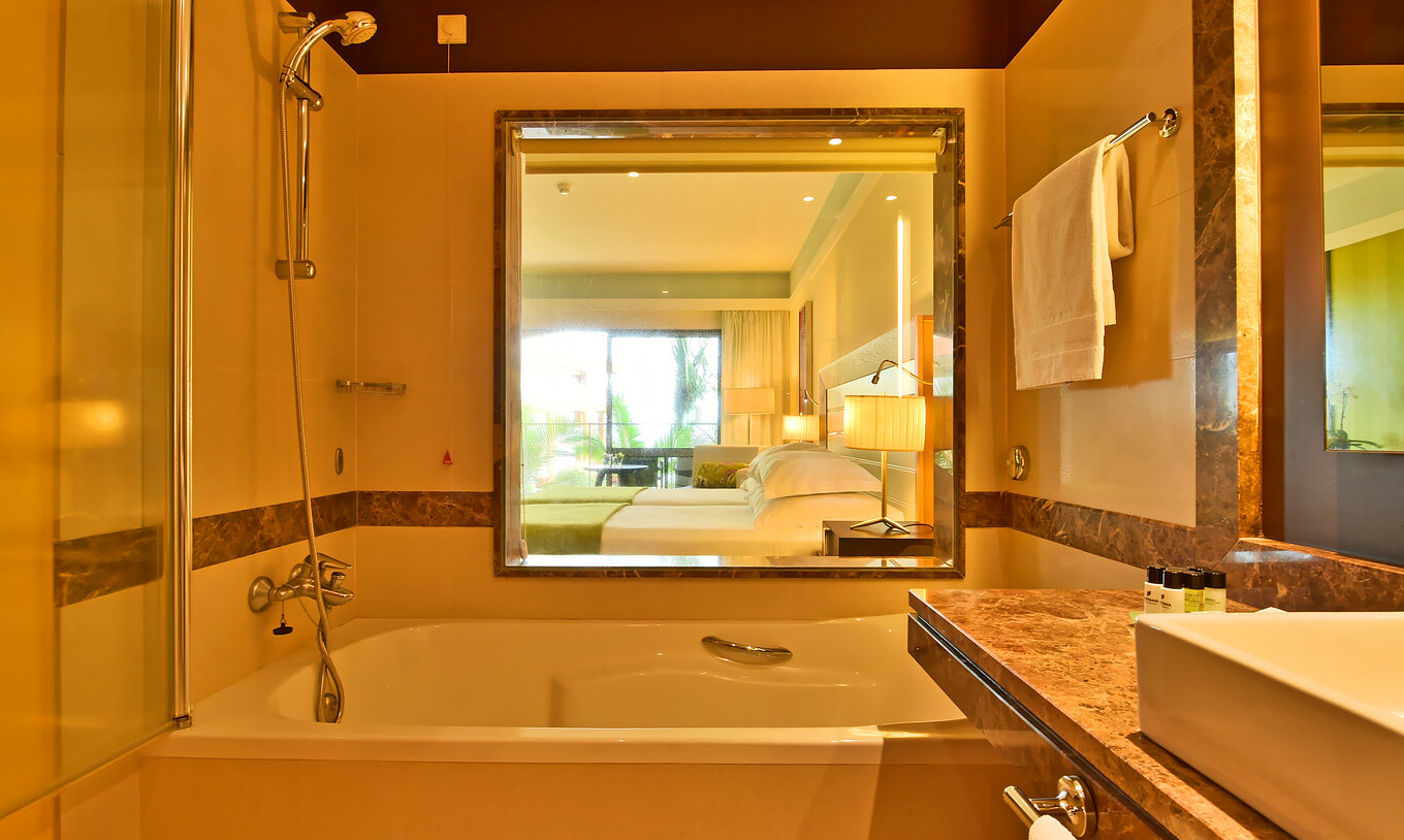 Das Superior Zimmer hat ein Bad mit Badewanne, Annehmlichkeiten und eine Glaswand zum Zimmer 