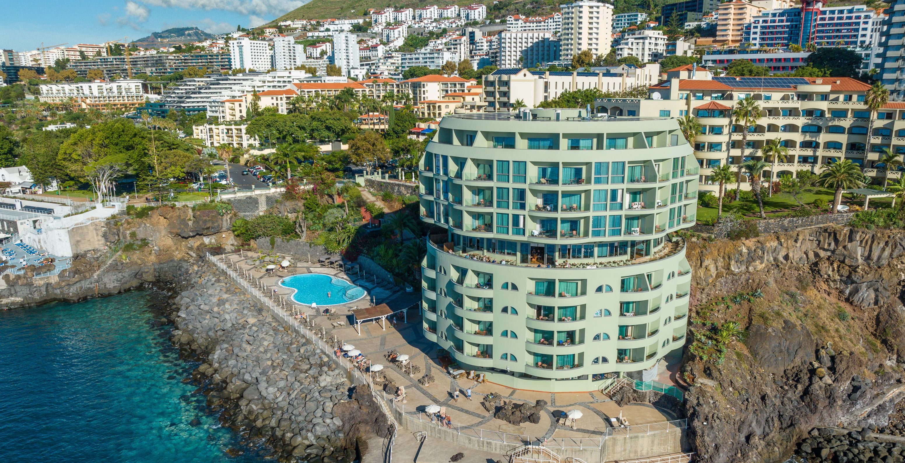 Blick auf das Pestana Vila Lido Madeira, ein Gebäude mit Außenpool, Liegestühlen und direktem Zugang zum Meer