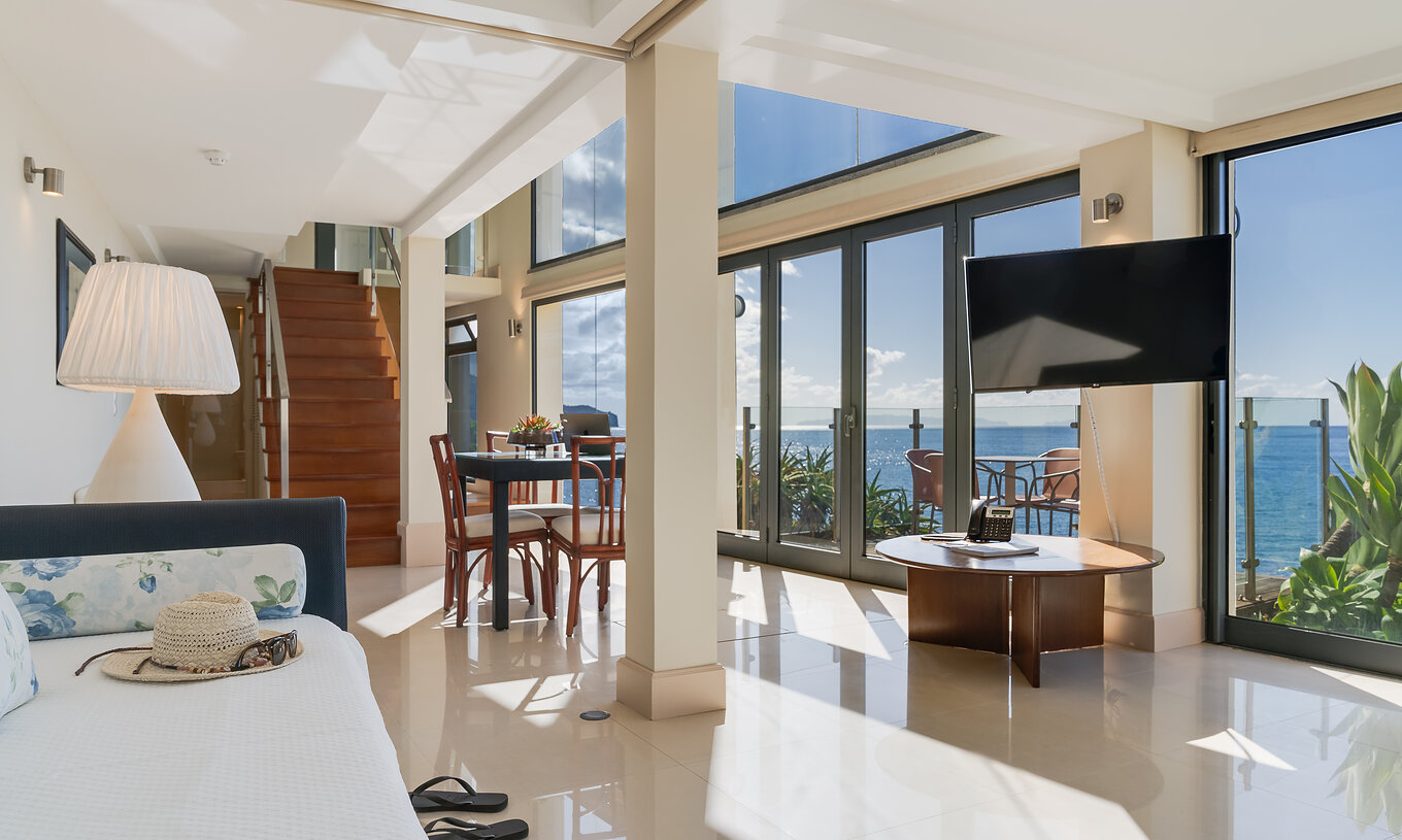 Suite Duplex Meerblick Pestana Vila Lido Madeira hat ein großes Wohnzimmer mit Meerblick, Sofa und Esszimmer