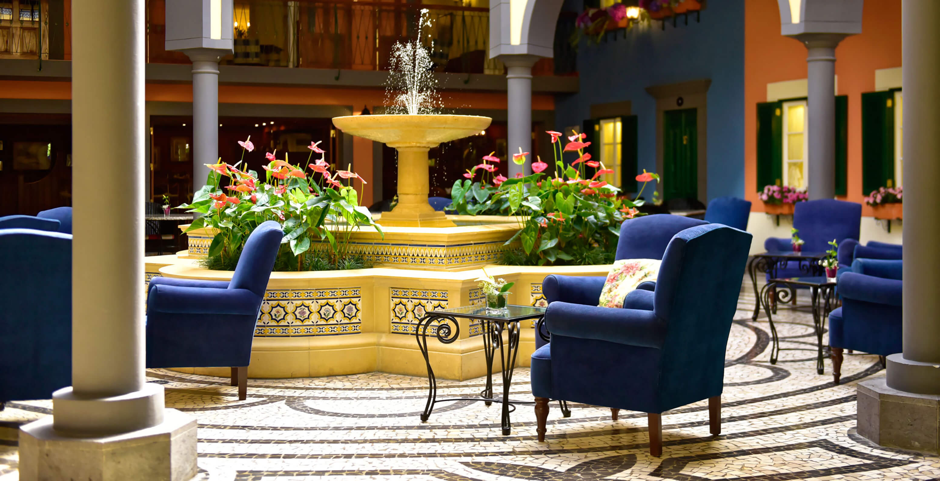 Innenhof mit zentralem Brunnen, rosa Blumen, blauen Sesseln im Pestana Village, Hotel mit Pool in Funchal