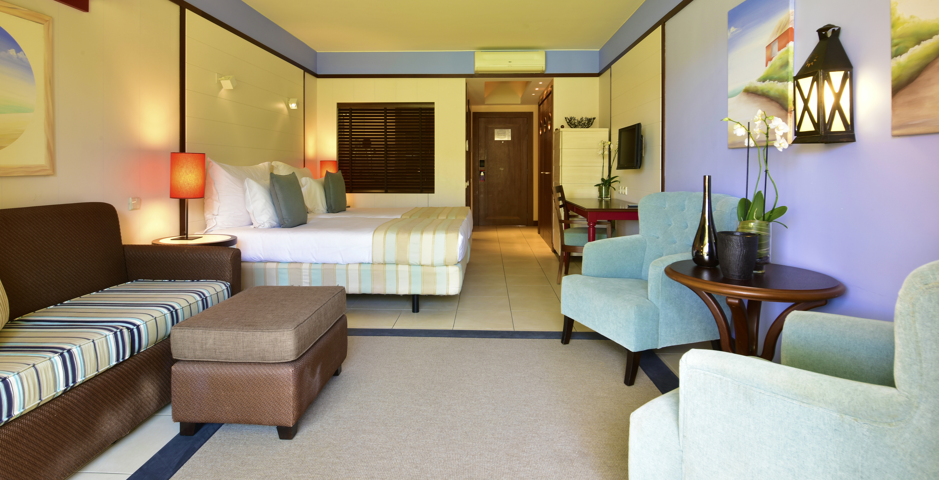 Das Doppelzimmer Poolblick hat ein Sofa, zwei Sessel, zwei Betten, Fernseher und Schreibtisch 