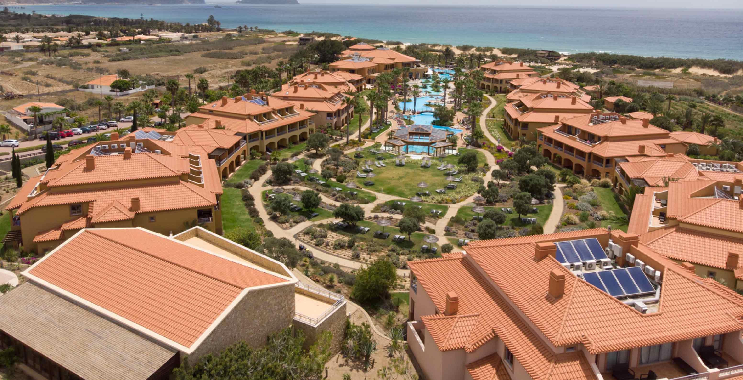 Drohnenblick auf das Pestana Porto Santo All Inclusive mit mehreren Villen rund um den Pool und das Grün