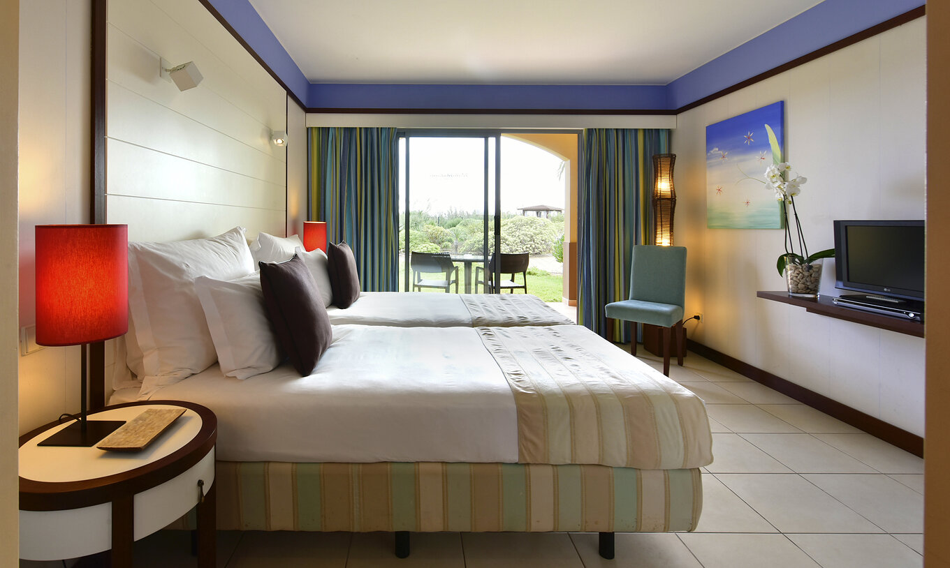 Das Doppelzimmer Klassik hat zwei Betten, einen Stuhl und einen Balkon mit Tisch und Gartenblick 