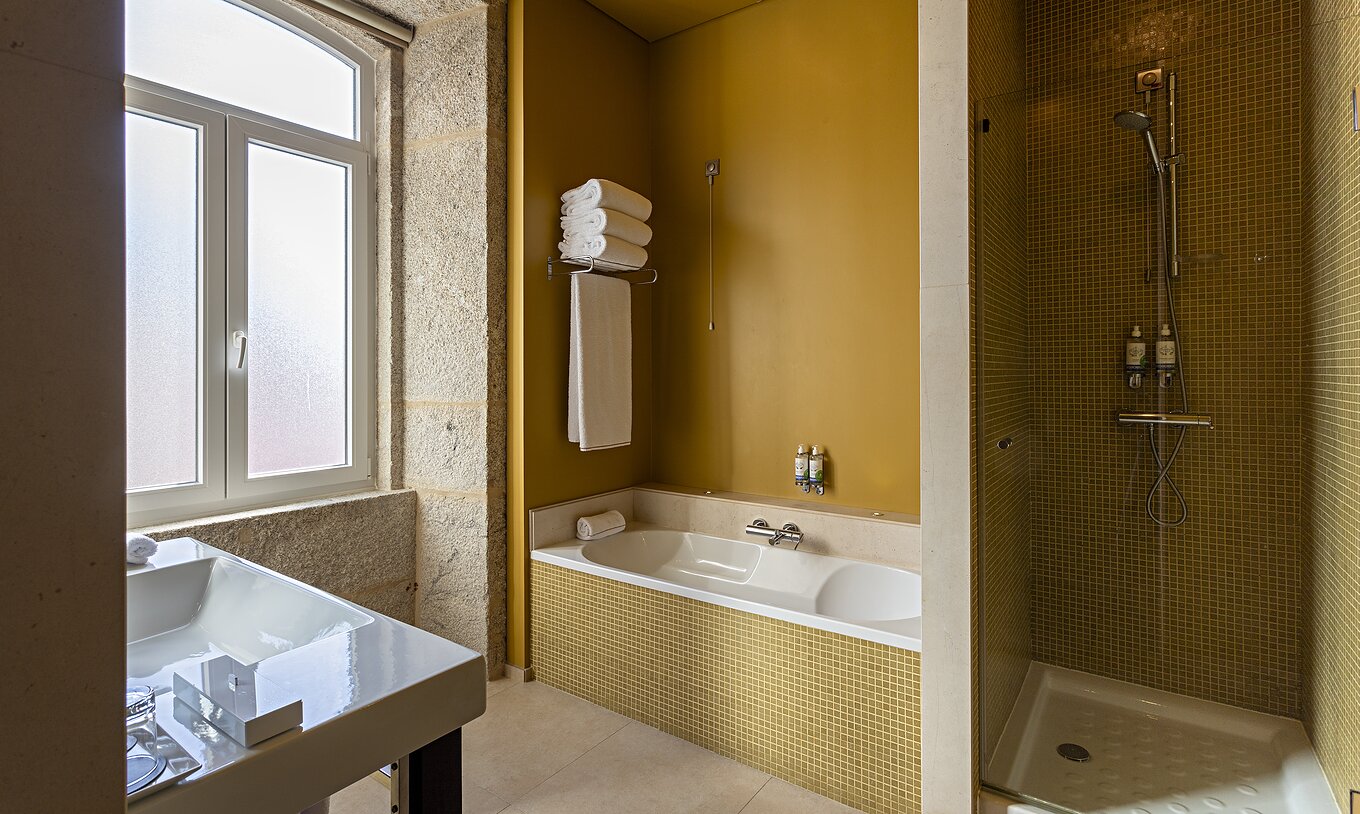 Die Suite Nasoni verfügt über ein Badezimmer mit gelben Fliesen, Badewanne und Duschbereich