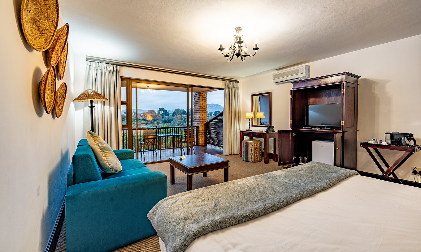 Das Premium Zimmer im Pestana Kruger Lodge hat Wohnbereich mit Sofa, Fernseher und afrikanischer Dekoration