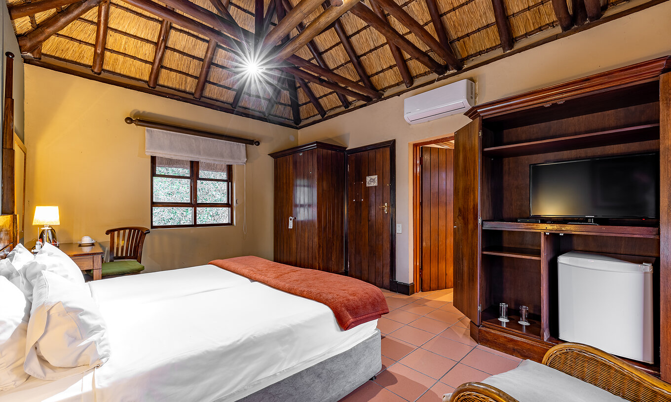 Das Standardzimmer im Pestana Kruger Lodge hat zwei Einzelbetten, Klimaanlage, Fernseher und Holzmobiliar