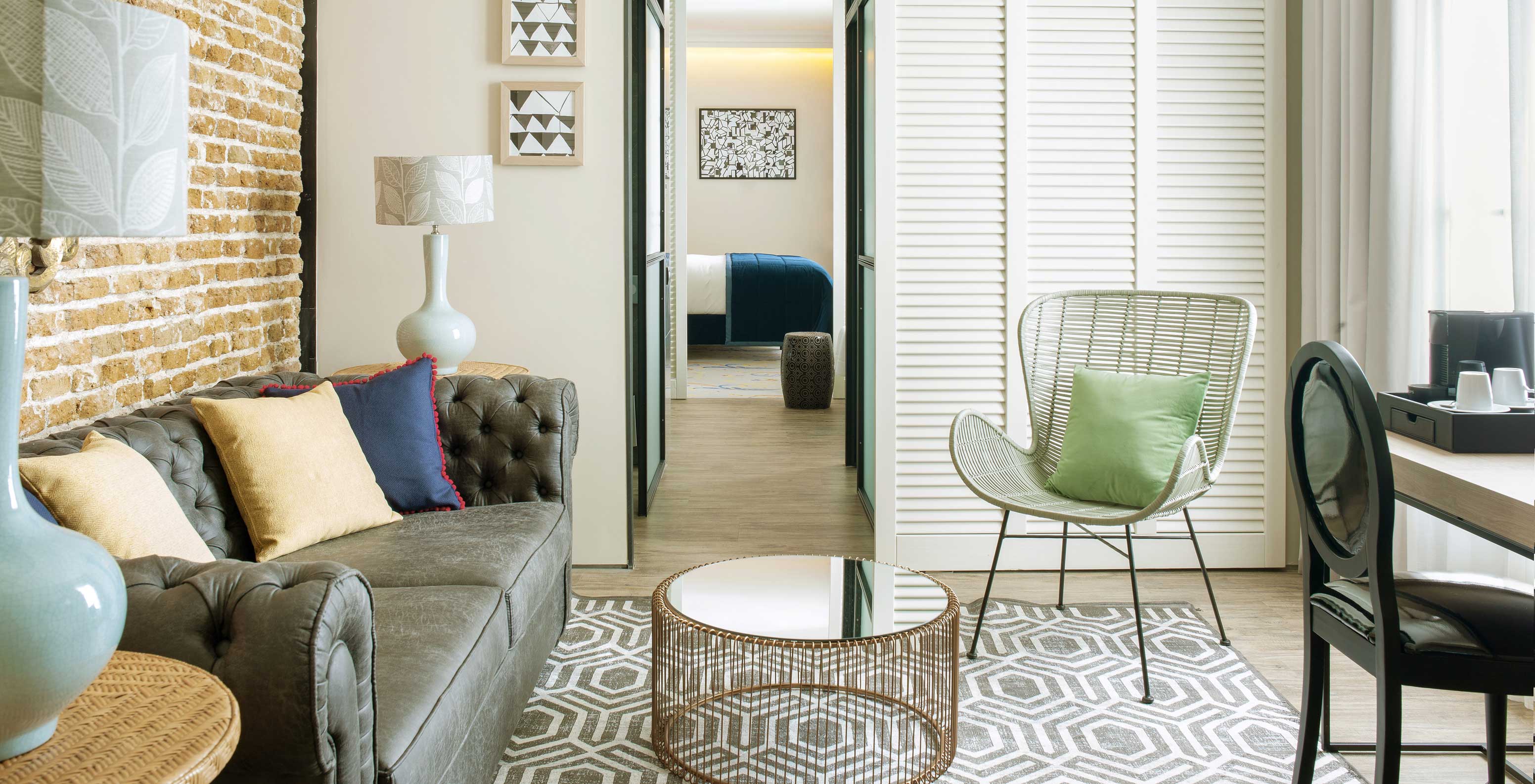 Die Suite im Pestana Plaza Mayor hat ein separates Wohnzimmer mit Sofa, Beistelltischen mit Lampen und Kaffeemaschine